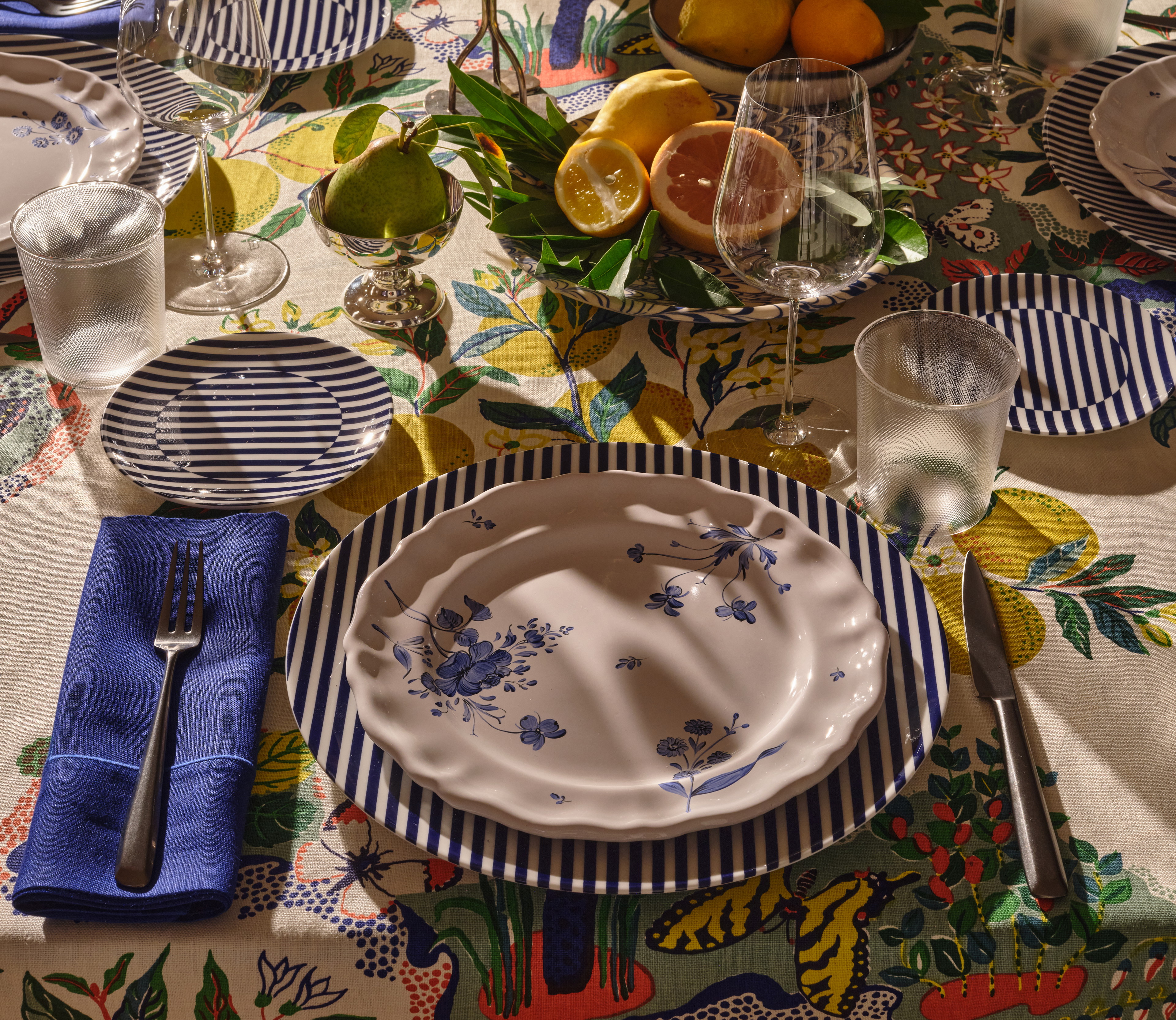 a table set with plates, silverware and fruit