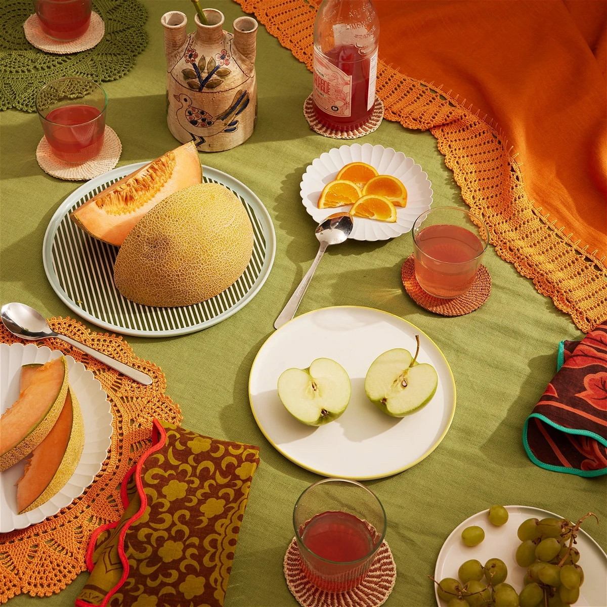 a table topped with plates of fruit and drinks