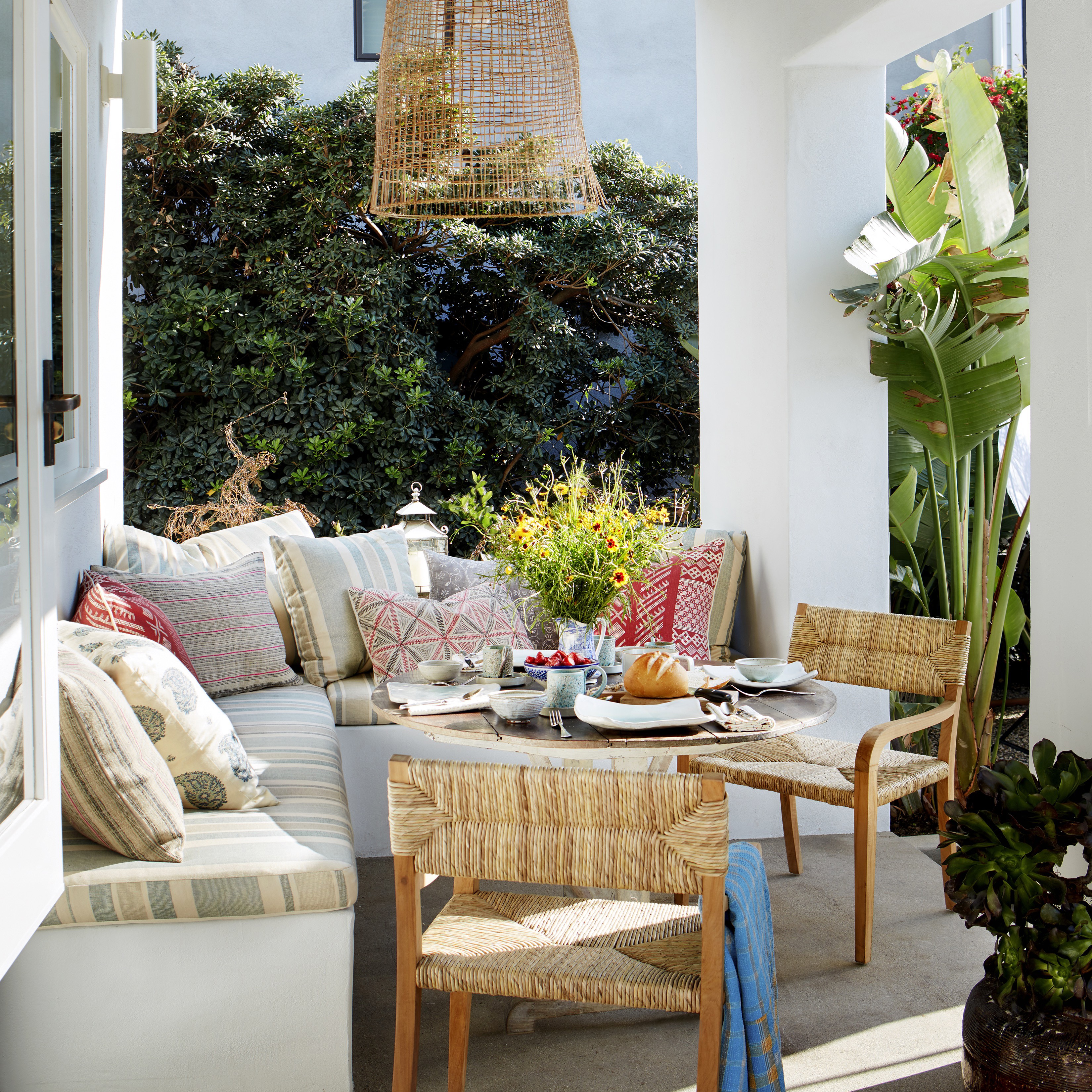 a patio with a couch, table, chairs and potted plants