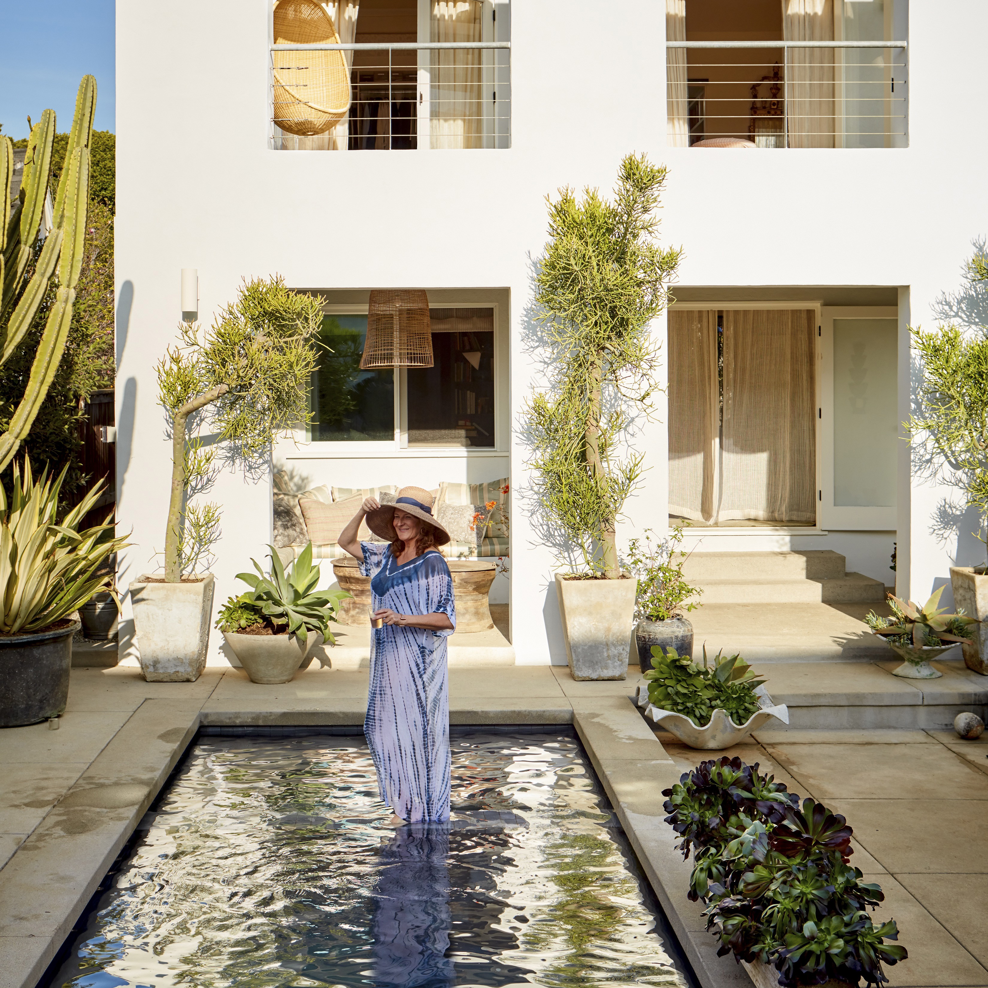 a woman standing in a pool in front of a house