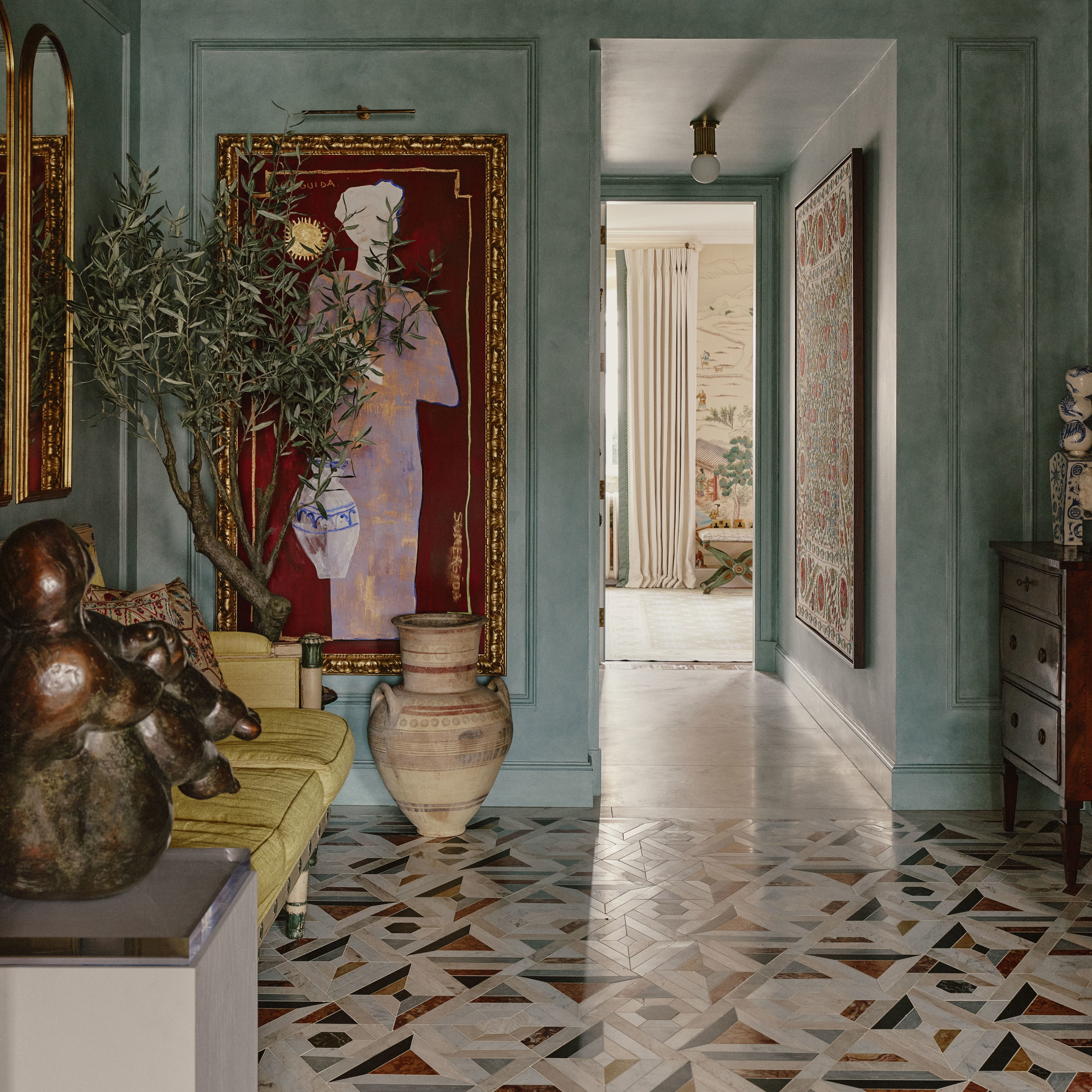 a hallway with a painting and a vase on the floor
