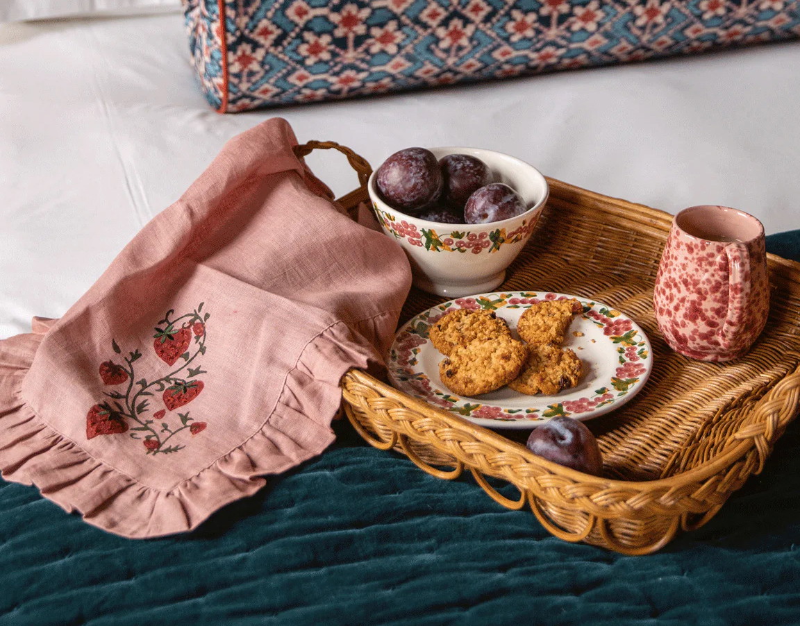 a tray of food sitting on a bed next to a pillow