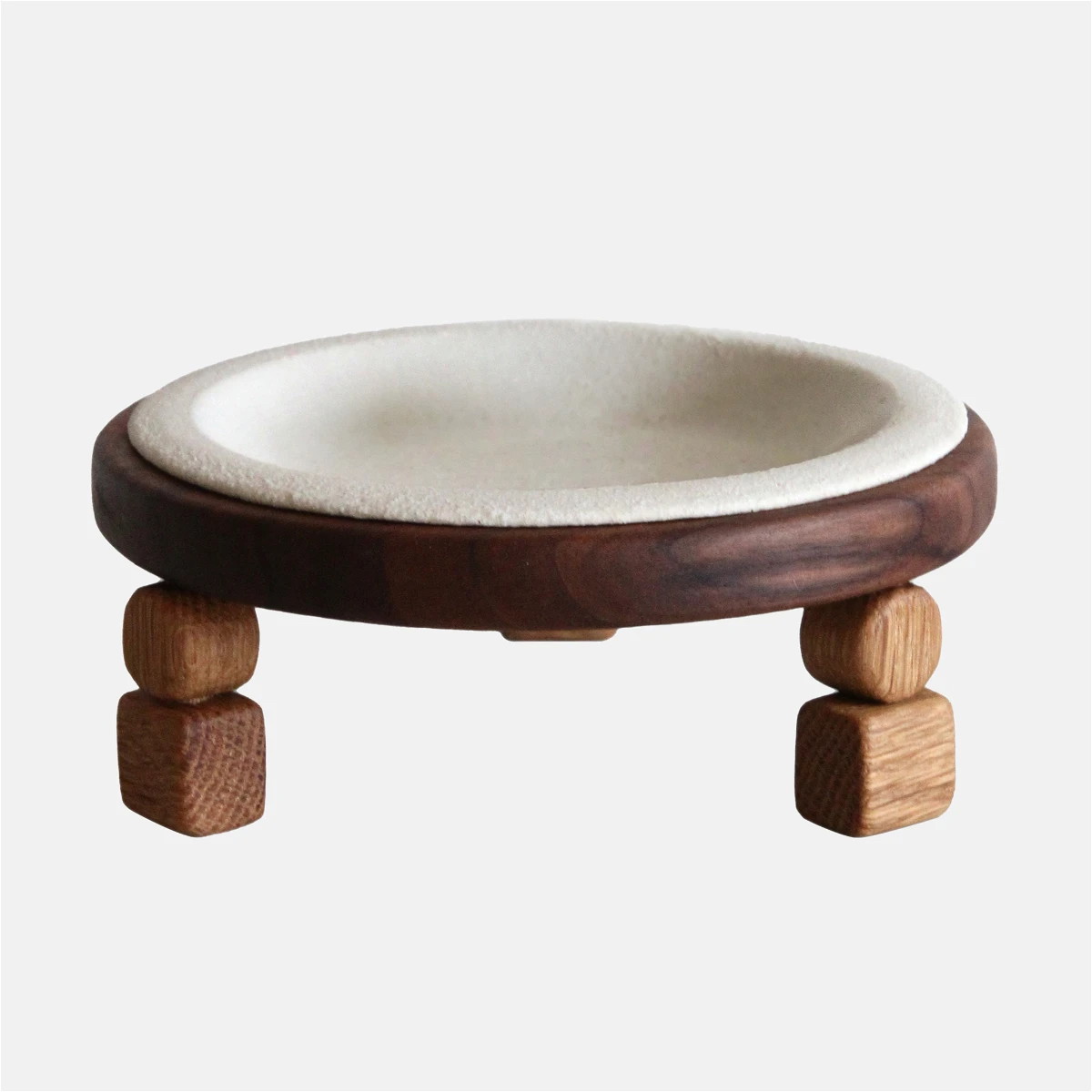 a white bowl with wooden legs and a wooden base