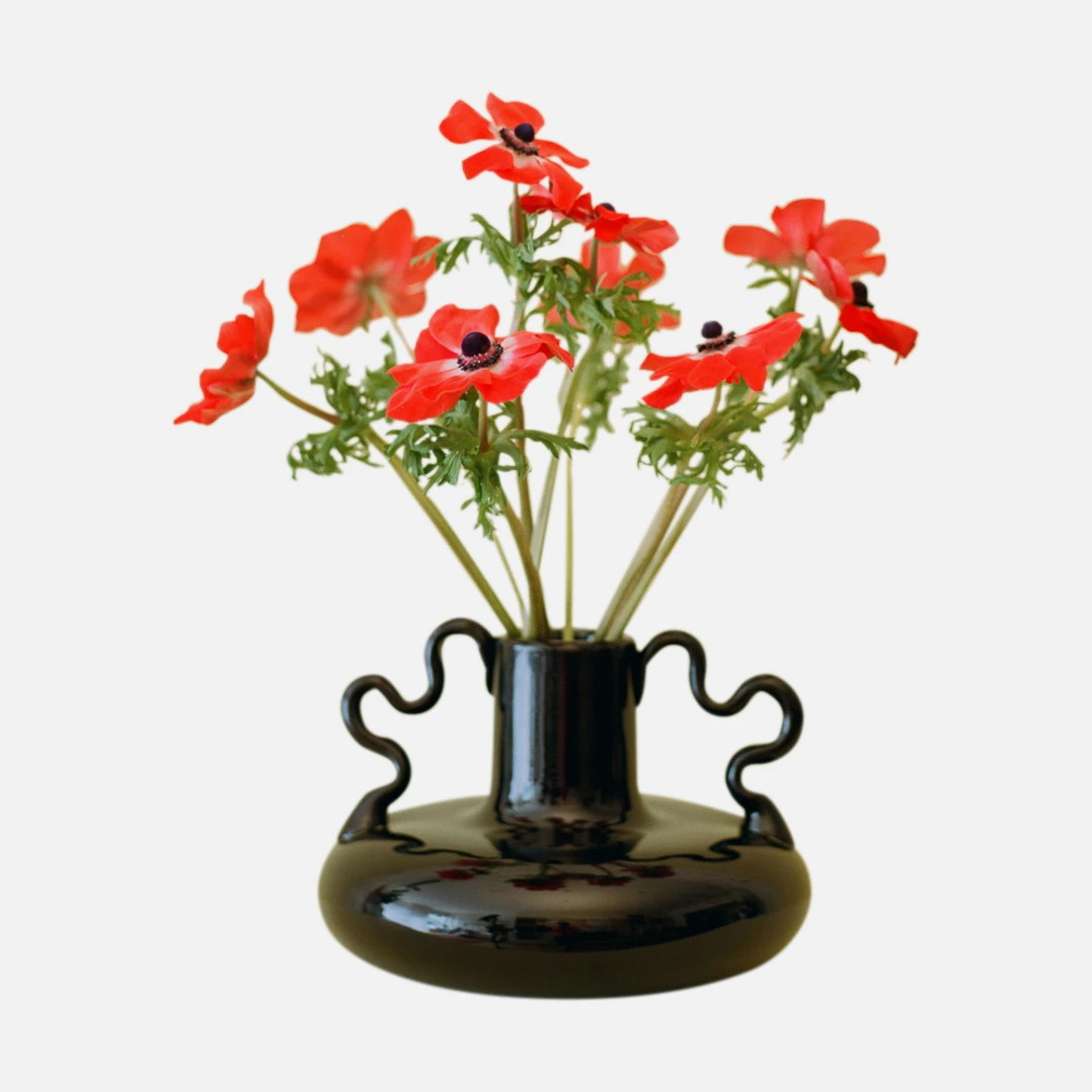 a black vase with red flowers in it