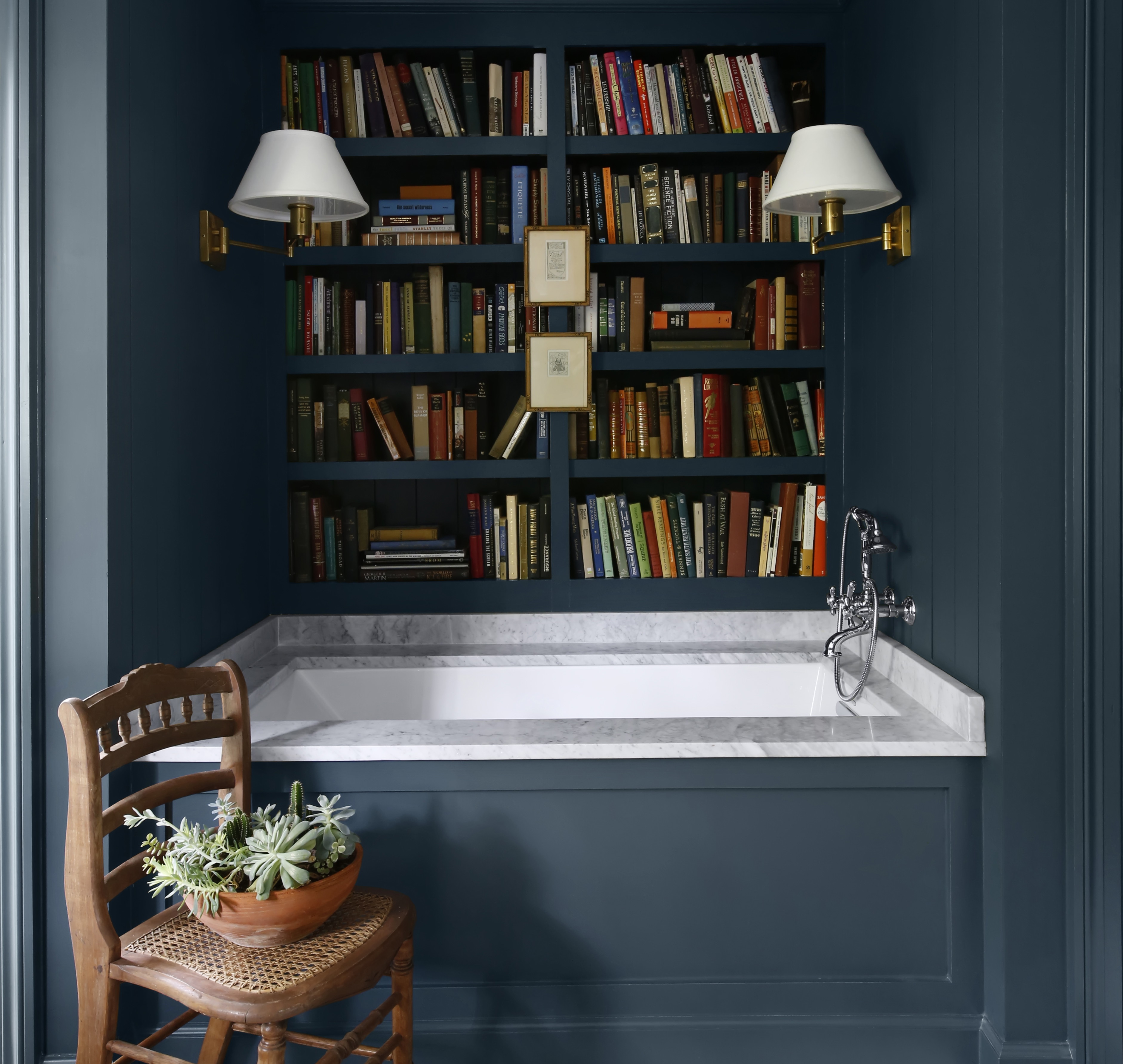 a bathroom with a tub, bookshelf and a chair