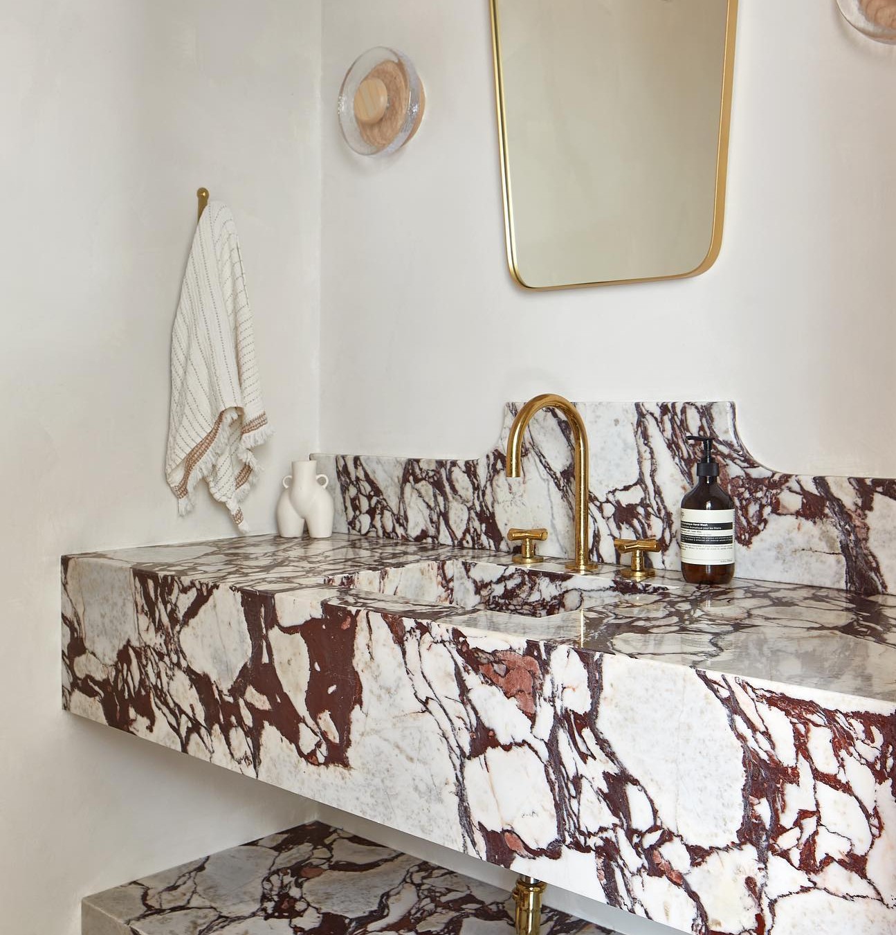 a bathroom with a marble counter top and gold faucet