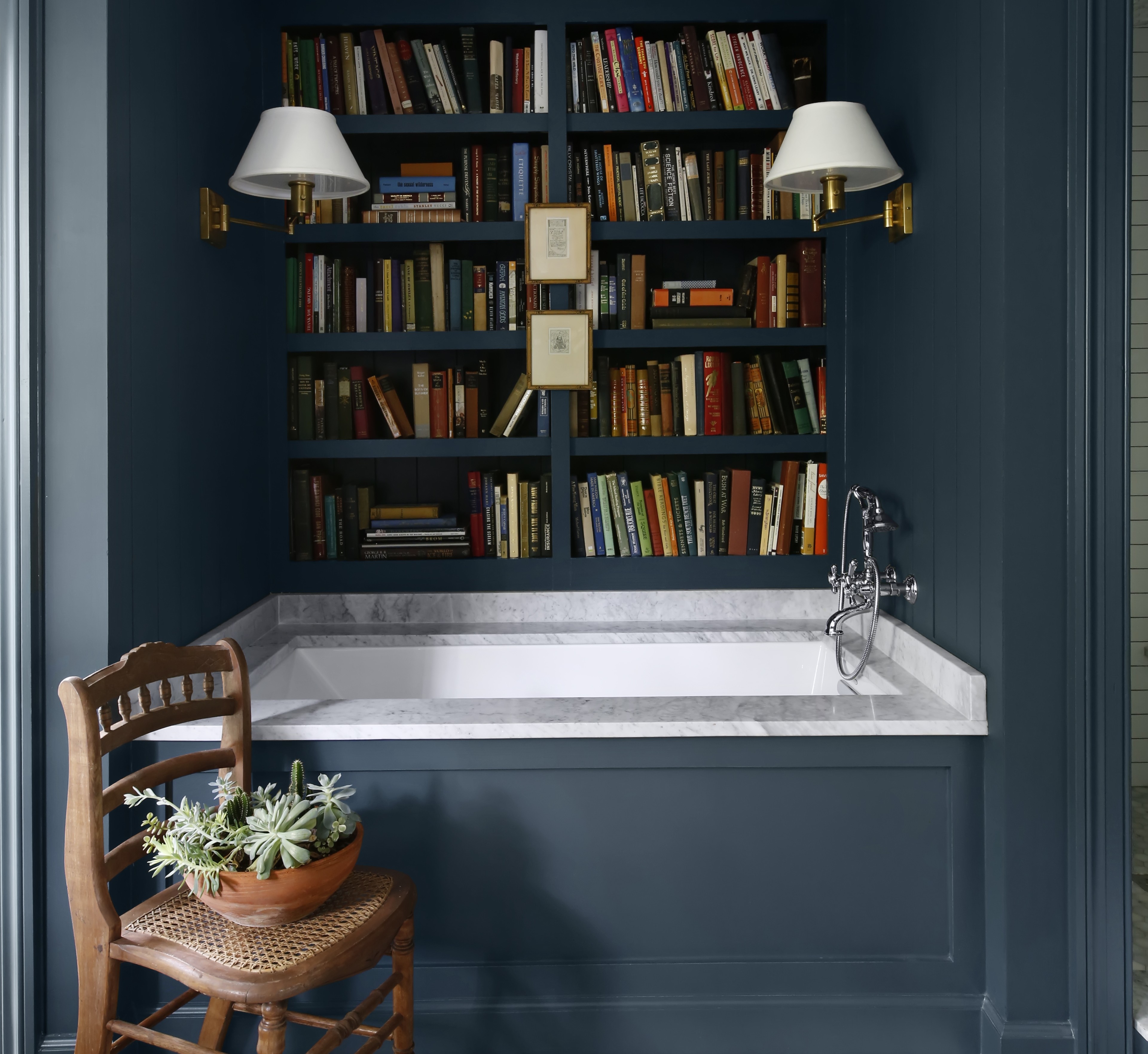 a bathroom with a tub, bookshelf and a chair
