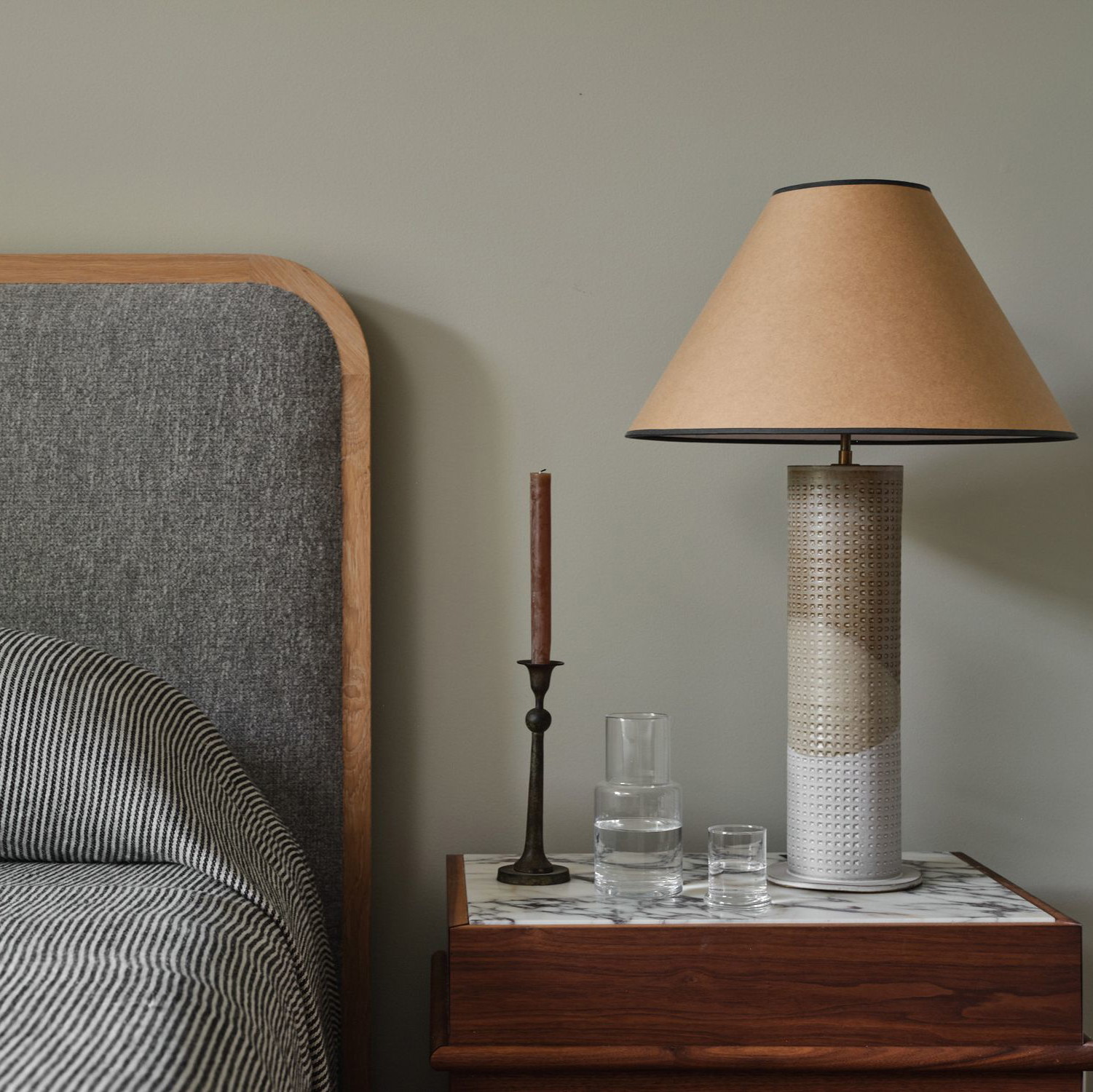 a bedroom with a bed, nightstand and lamp