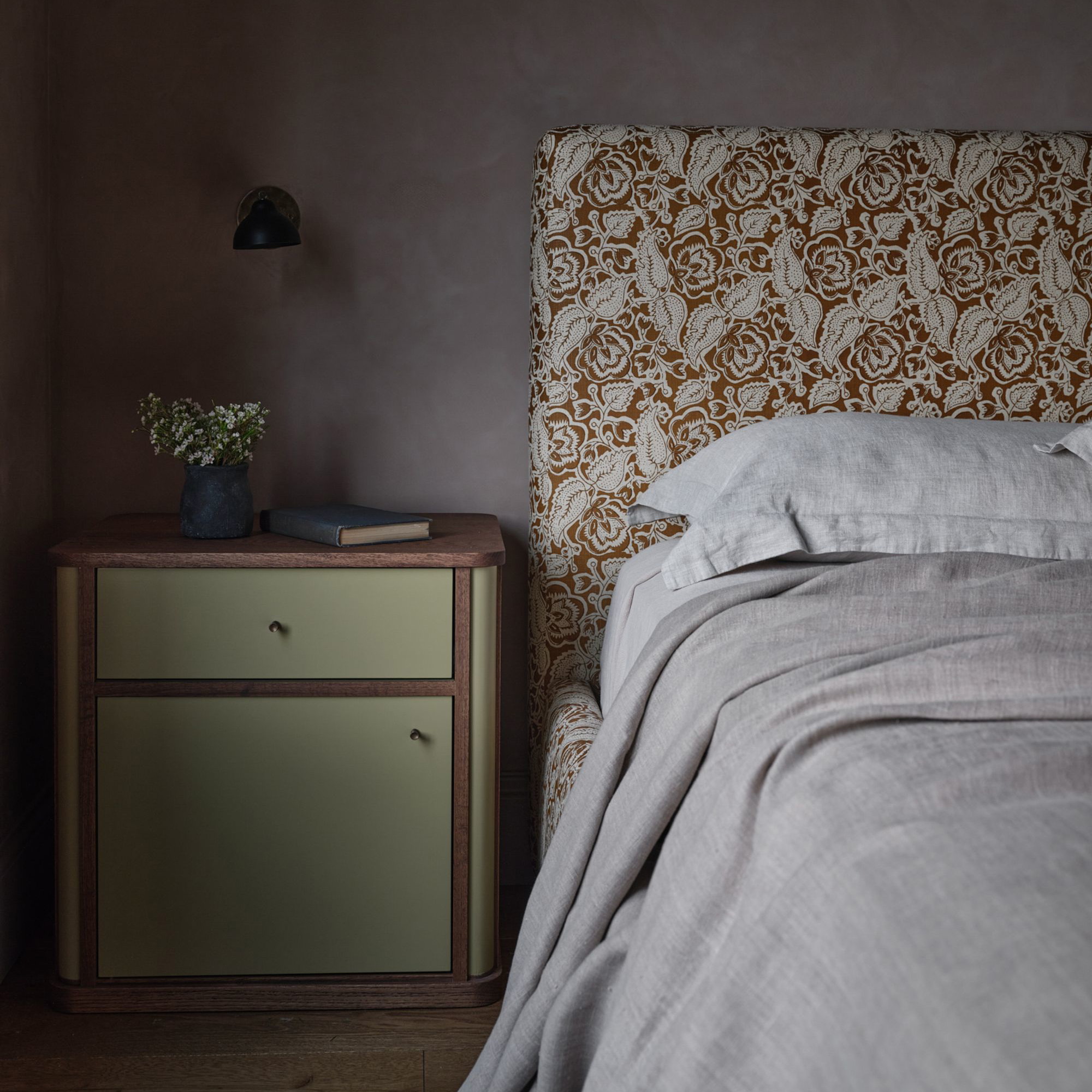 a bed sitting next to a night stand with a lamp on top of it