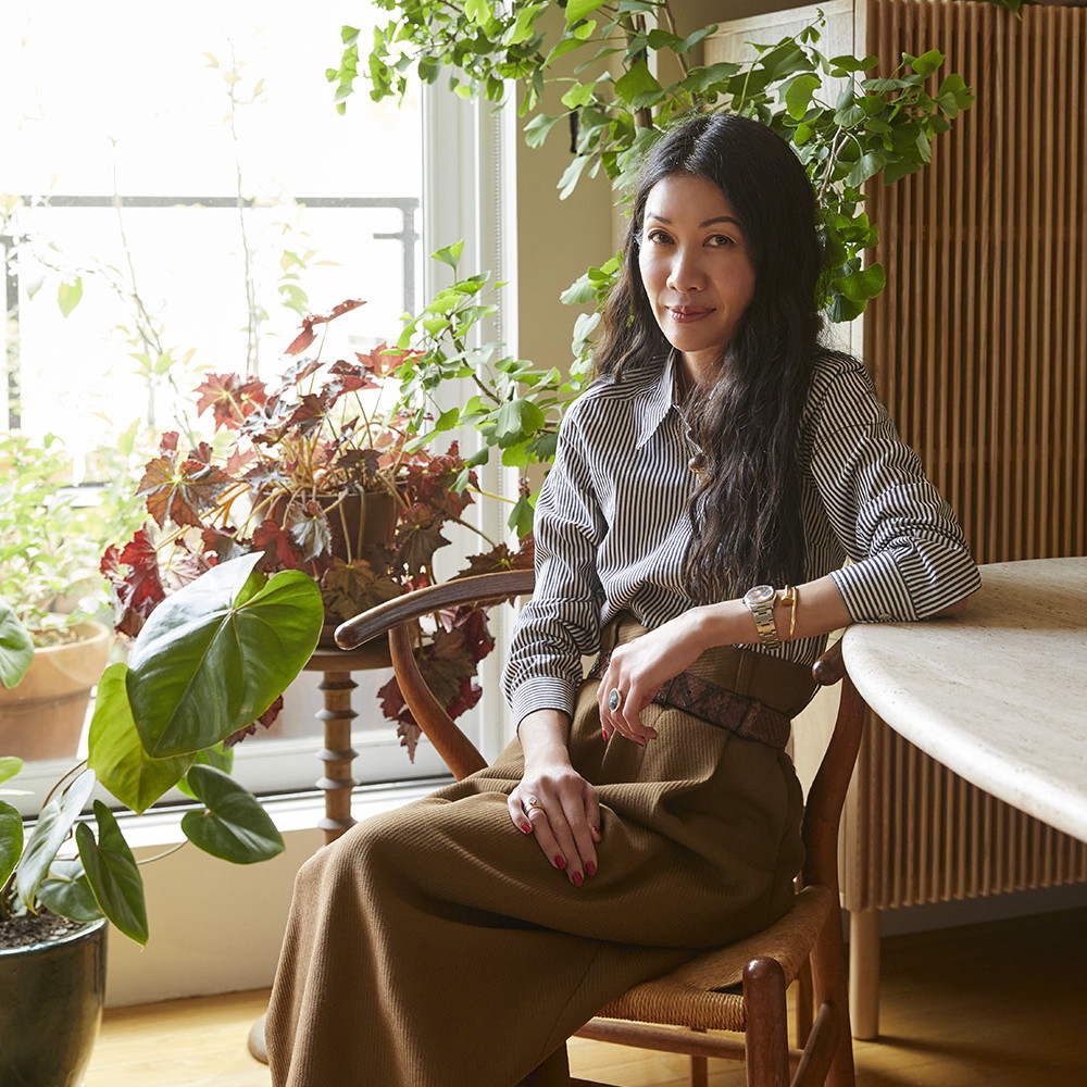 a woman sitting in a chair next to a potted plant