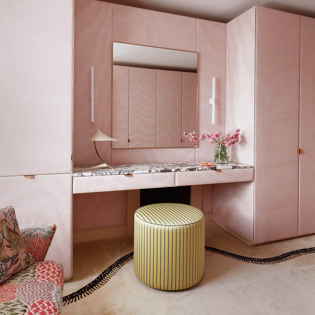 a pink bathroom with a vanity and stool