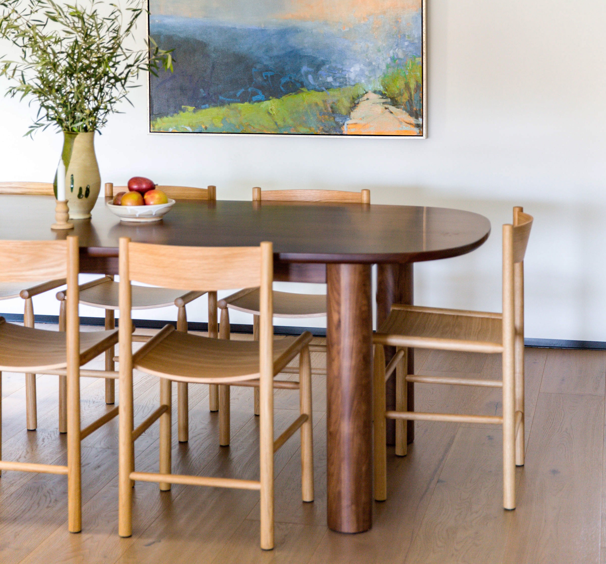 a painting hangs above a dining room table