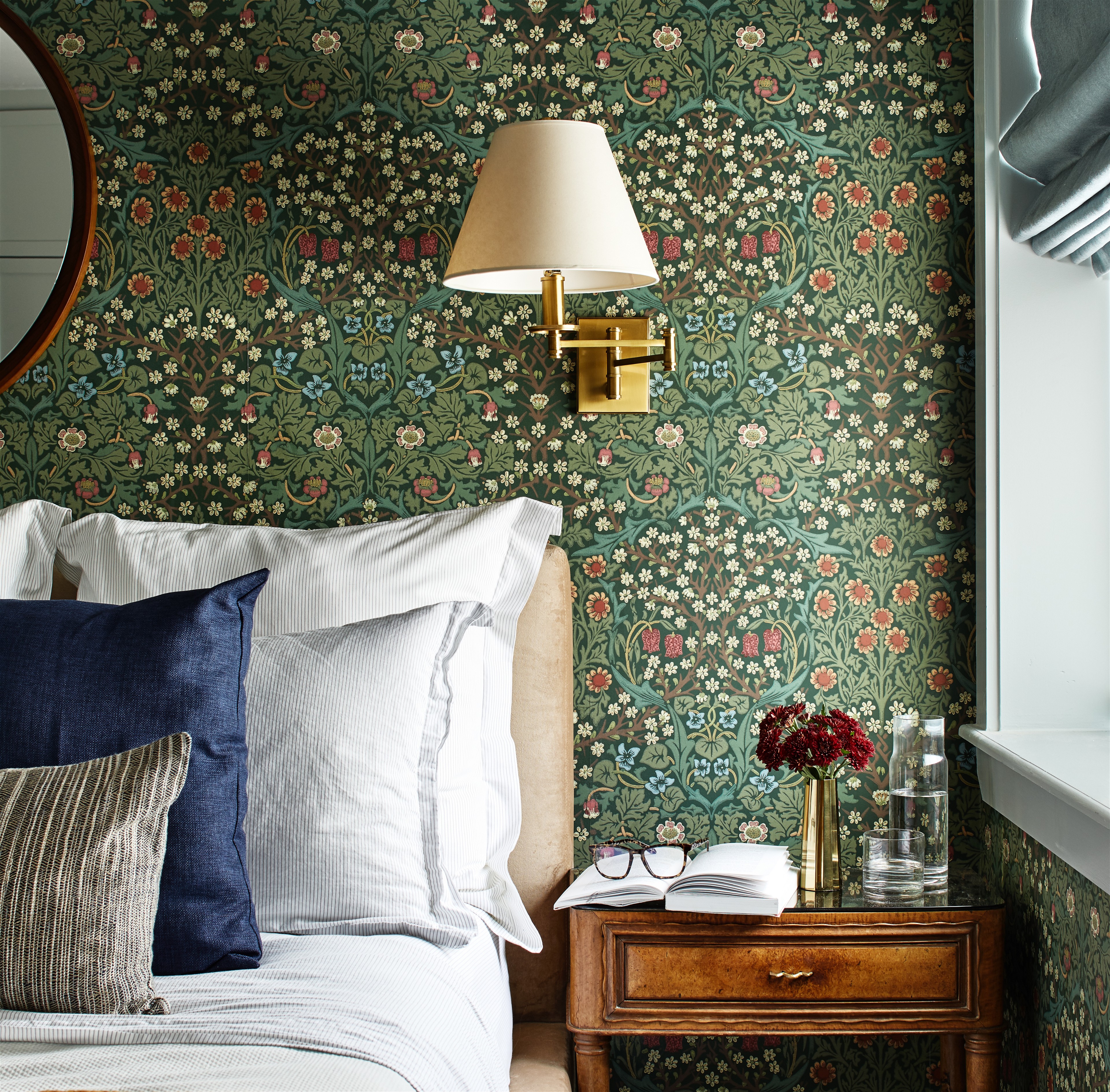 a bedroom with a floral wallpaper and a mirror