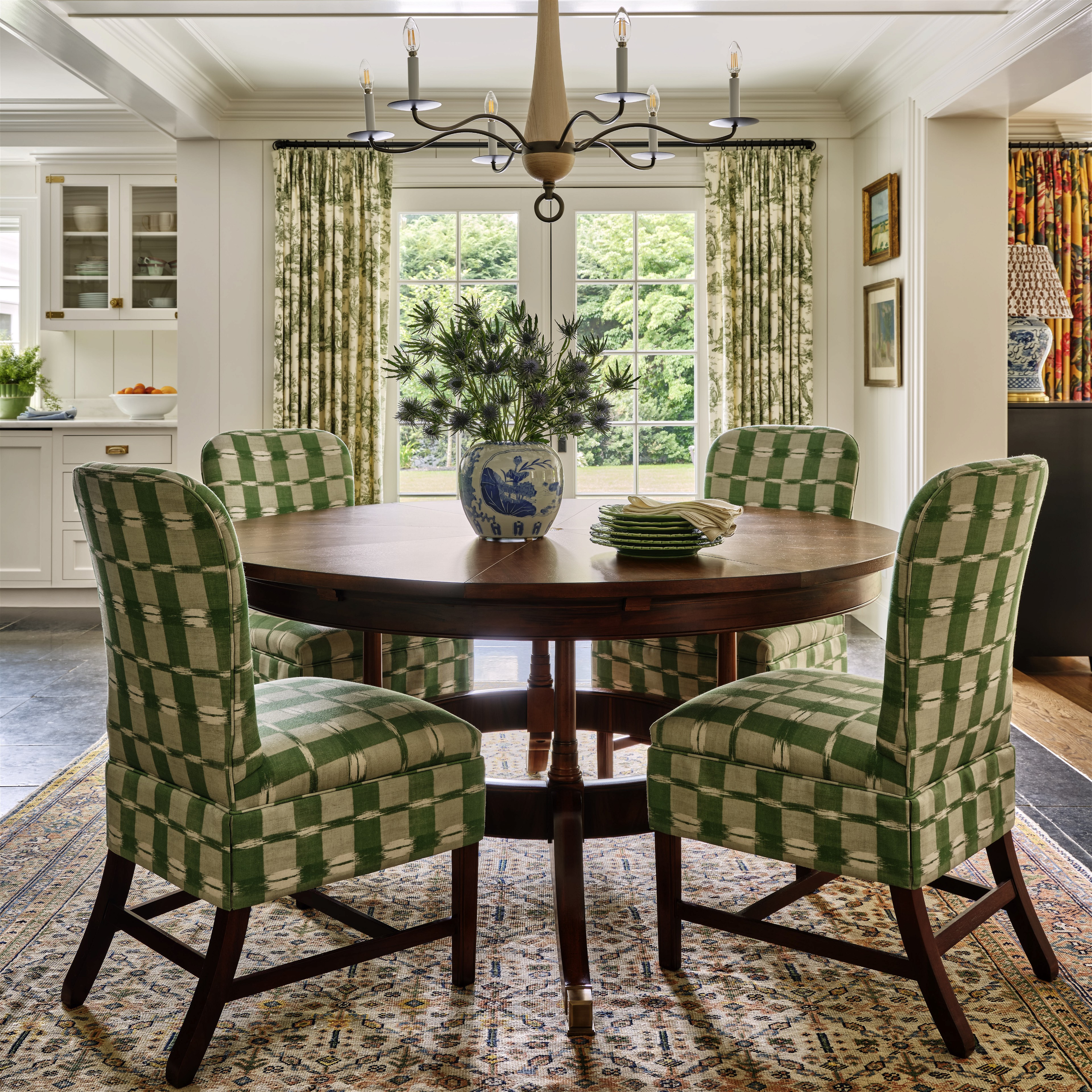 a dining room table with green chairs and a chandelier