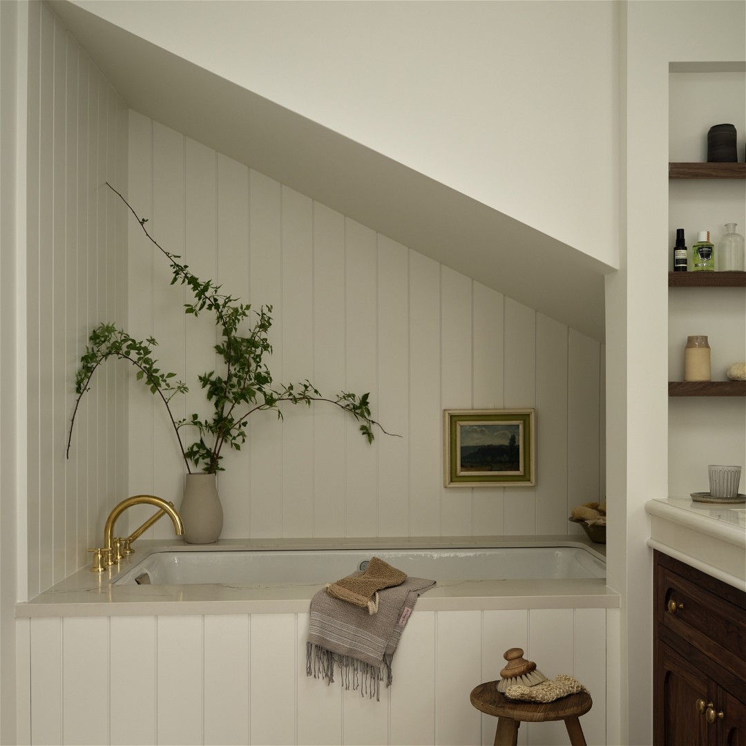 a bath room with a bath tub a stool and a plant