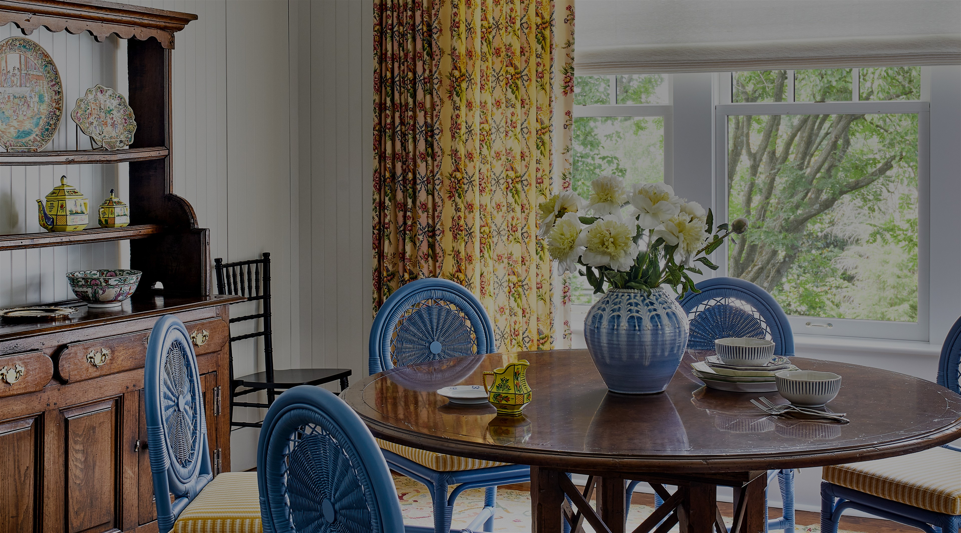 a dining room table with blue chairs and a vase of flowers