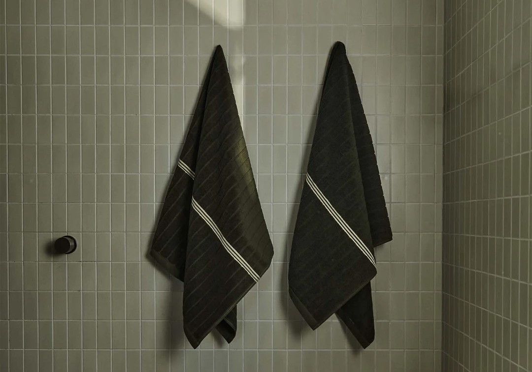 two black towels hanging on the wall of a bathroom