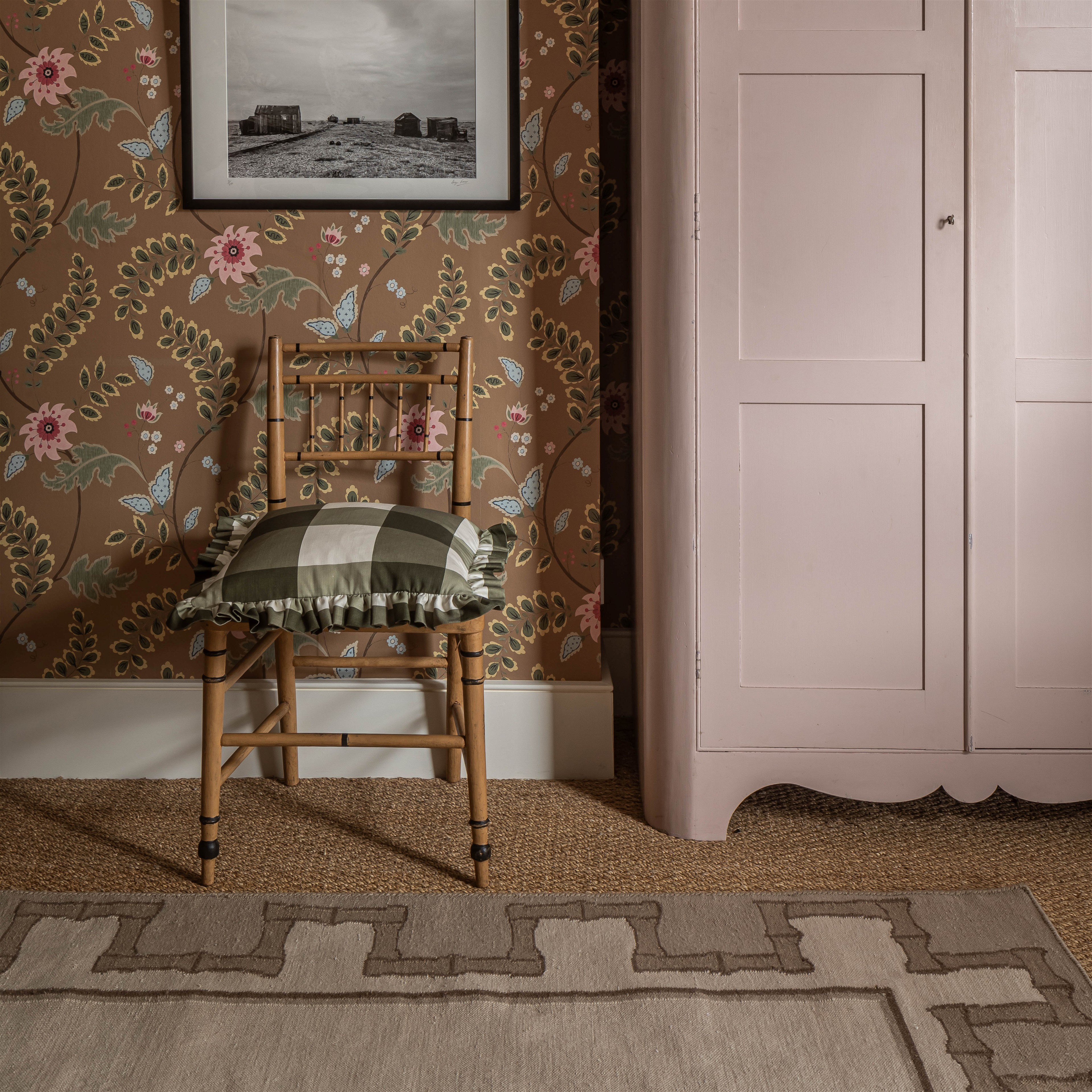 a pink armoire in a room with a floral wallpaper