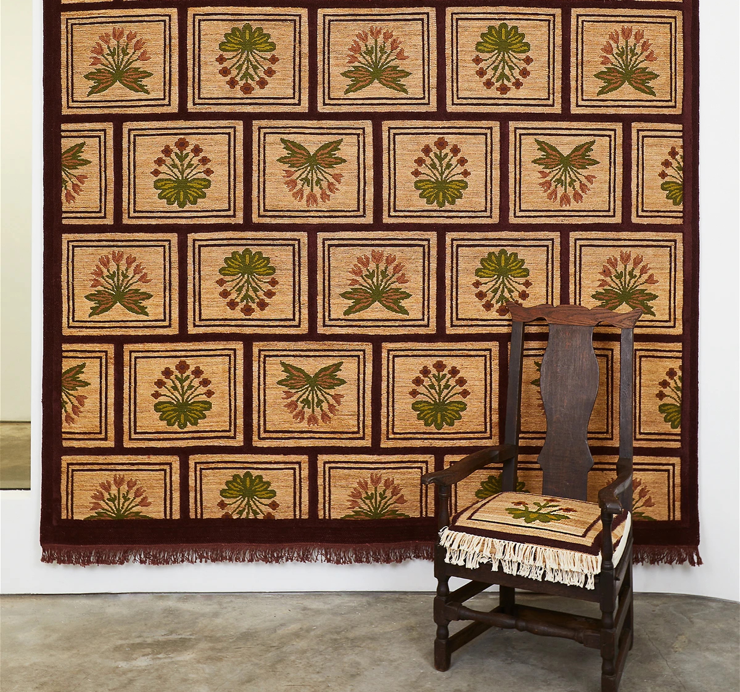 a chair sitting in front of a wall with a tapestry on it