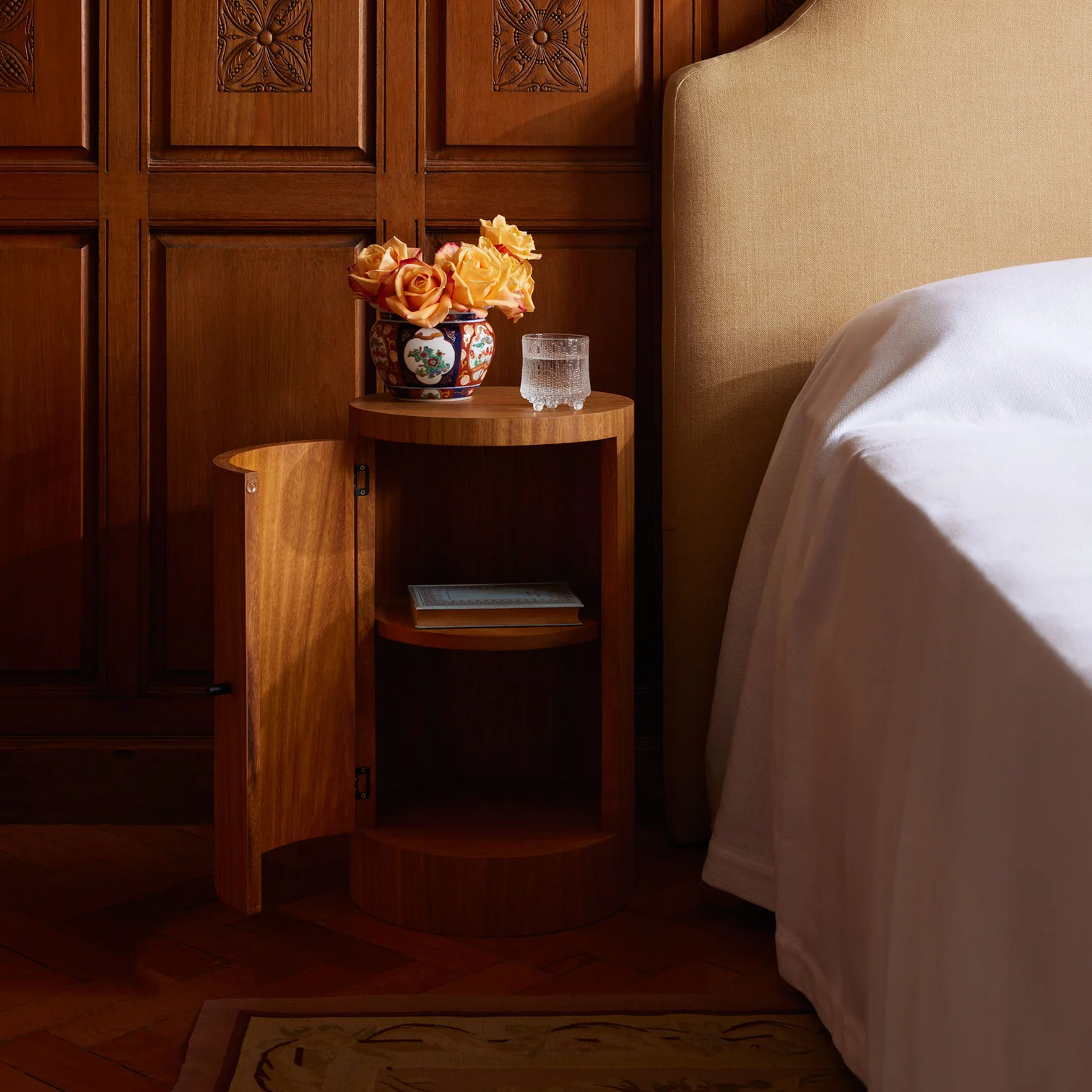 a bed with a wooden headboard and a small table with flowers on it