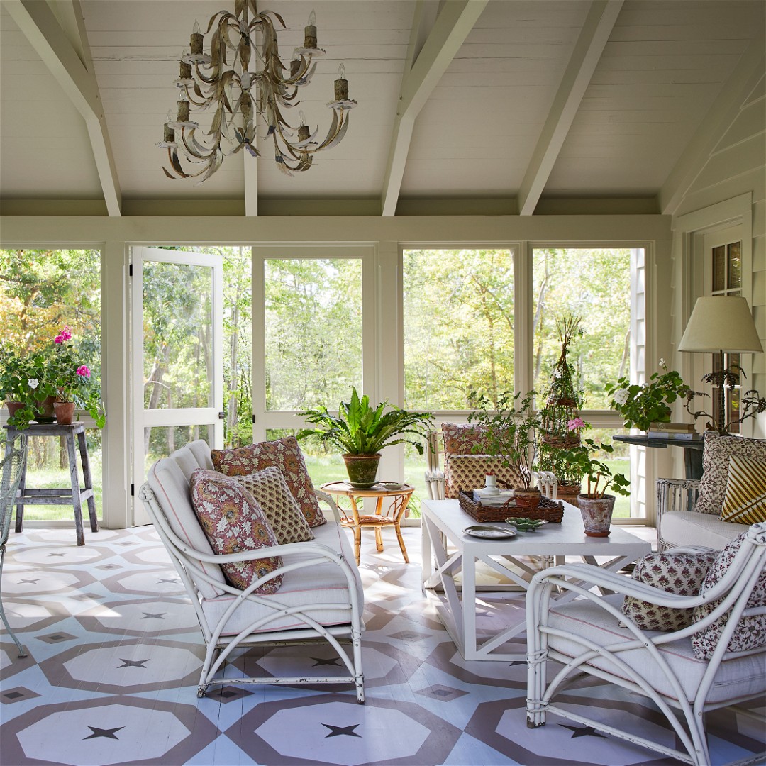 a sun room with a table, chairs and a chandelier