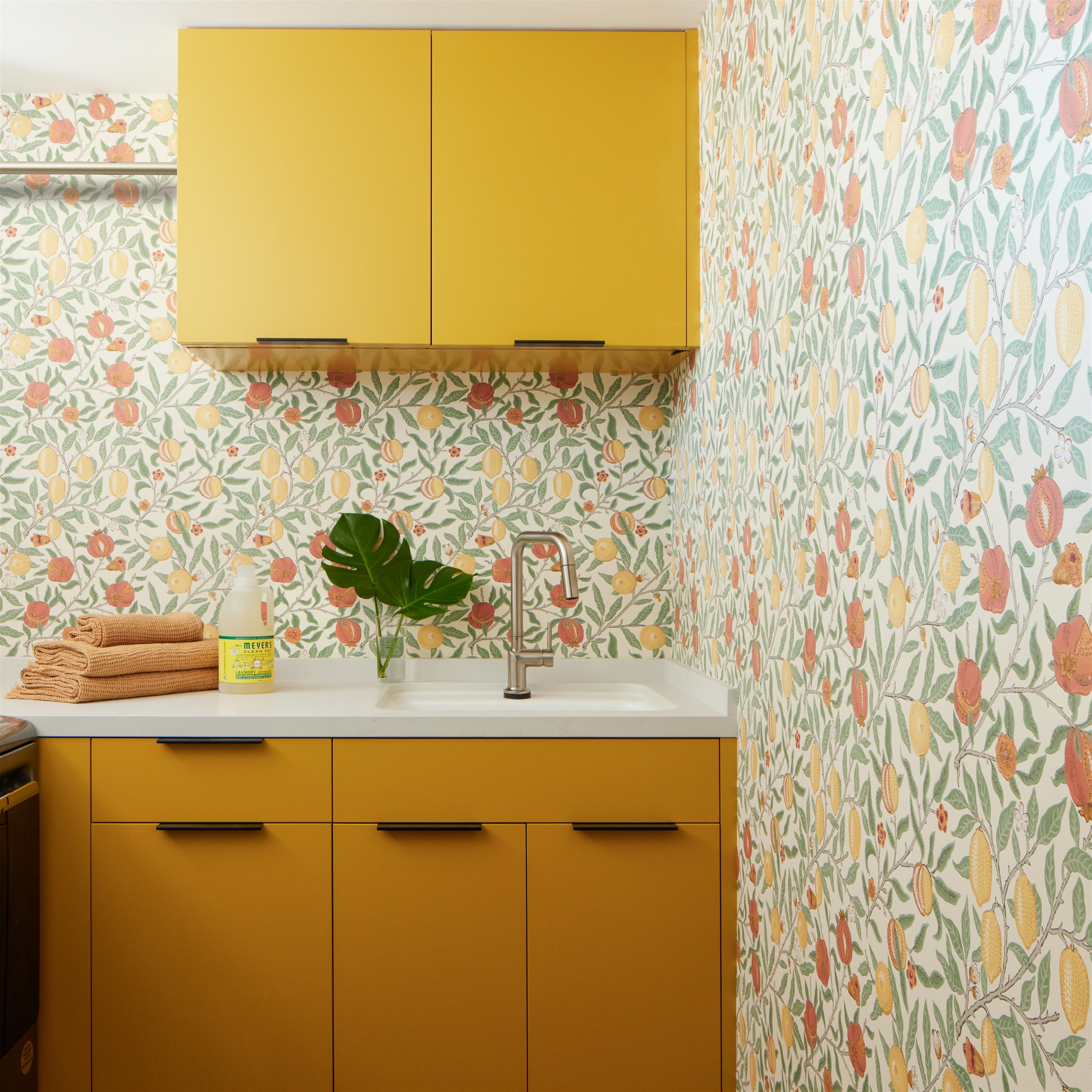 a kitchen with yellow cabinets and a floral wallpaper