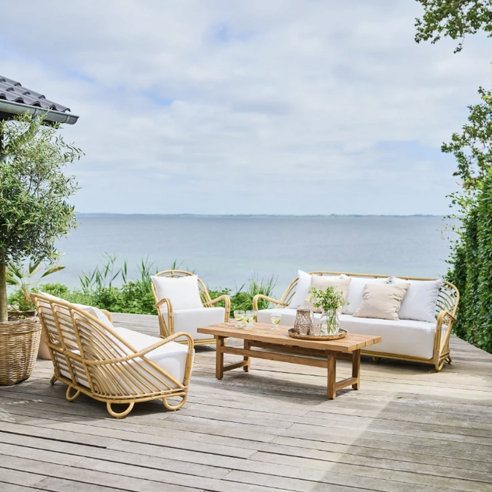 a wooden deck with wicker furniture and a view of the ocean