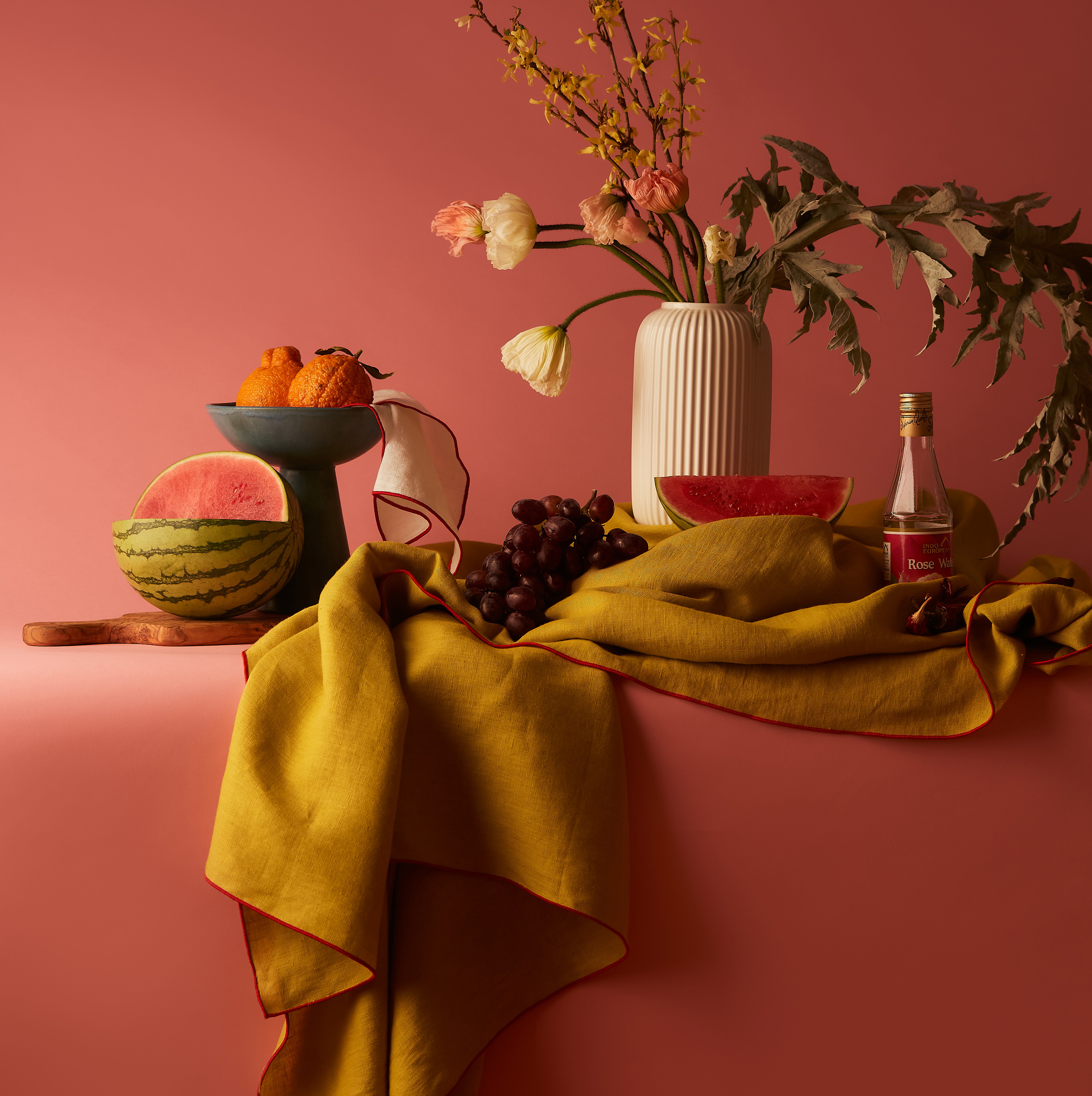 a table topped with a vase filled with flowers and fruit