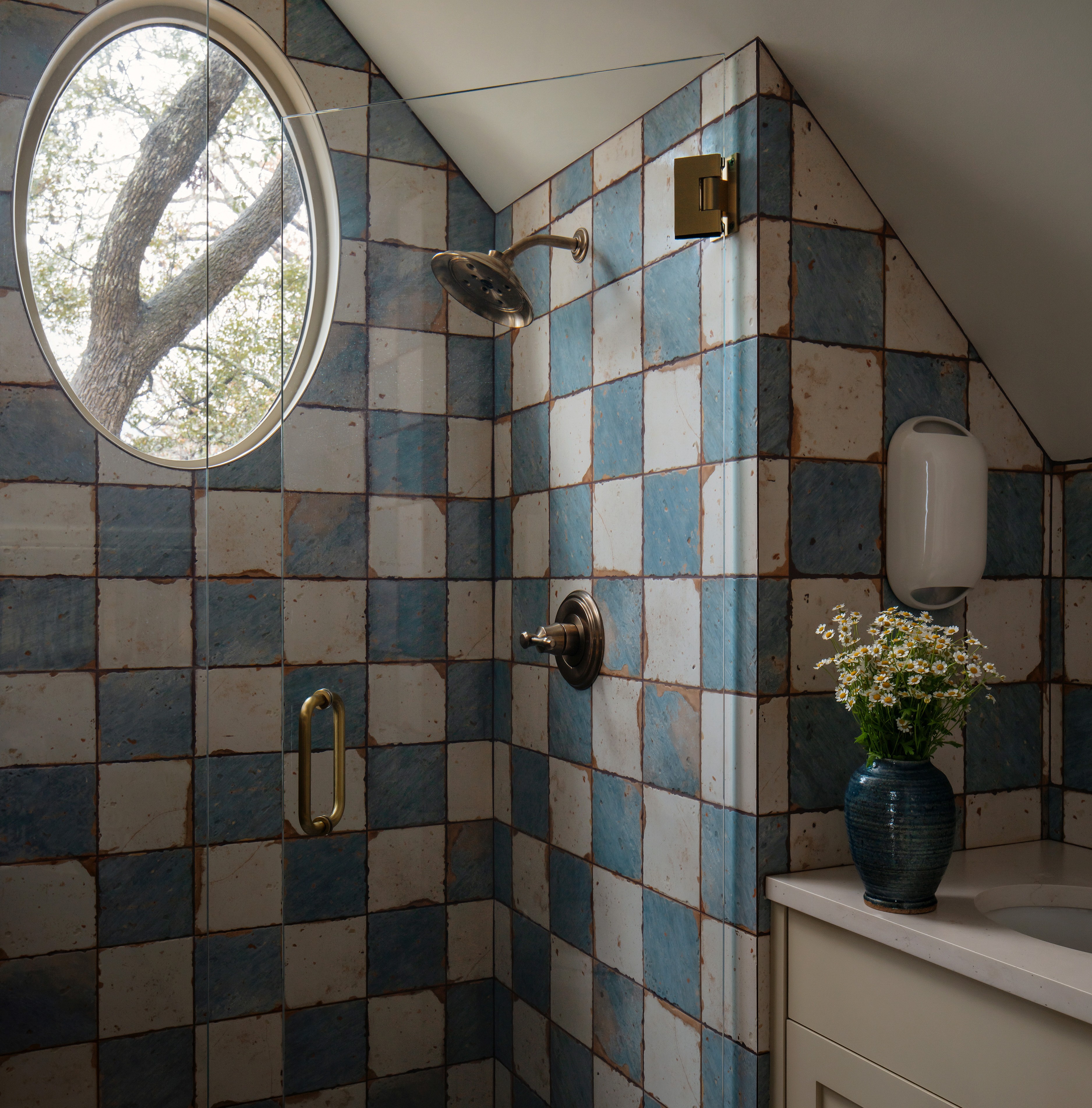 a blue and white tiled shower with a round window