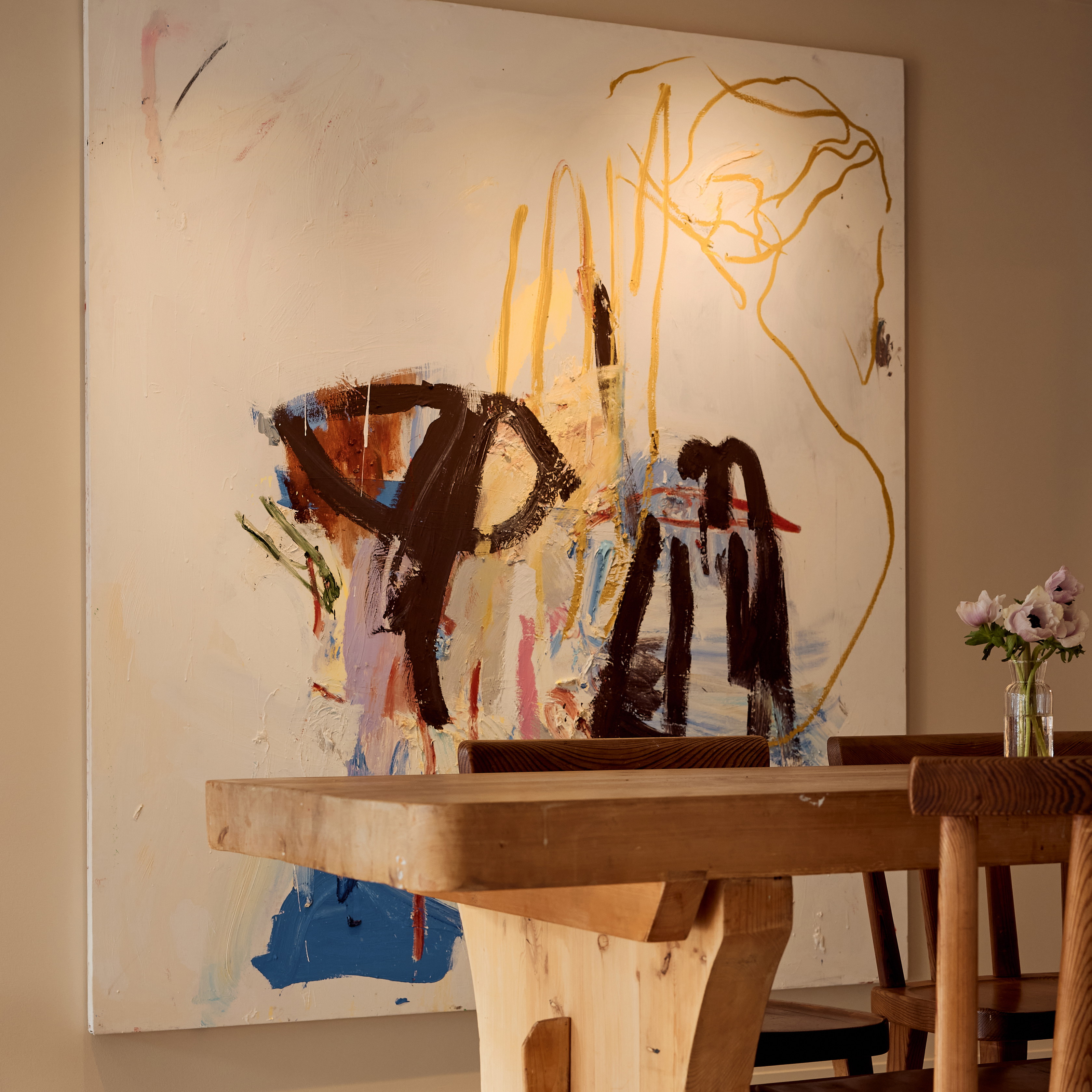 a wooden table with chairs and a painting on the wall