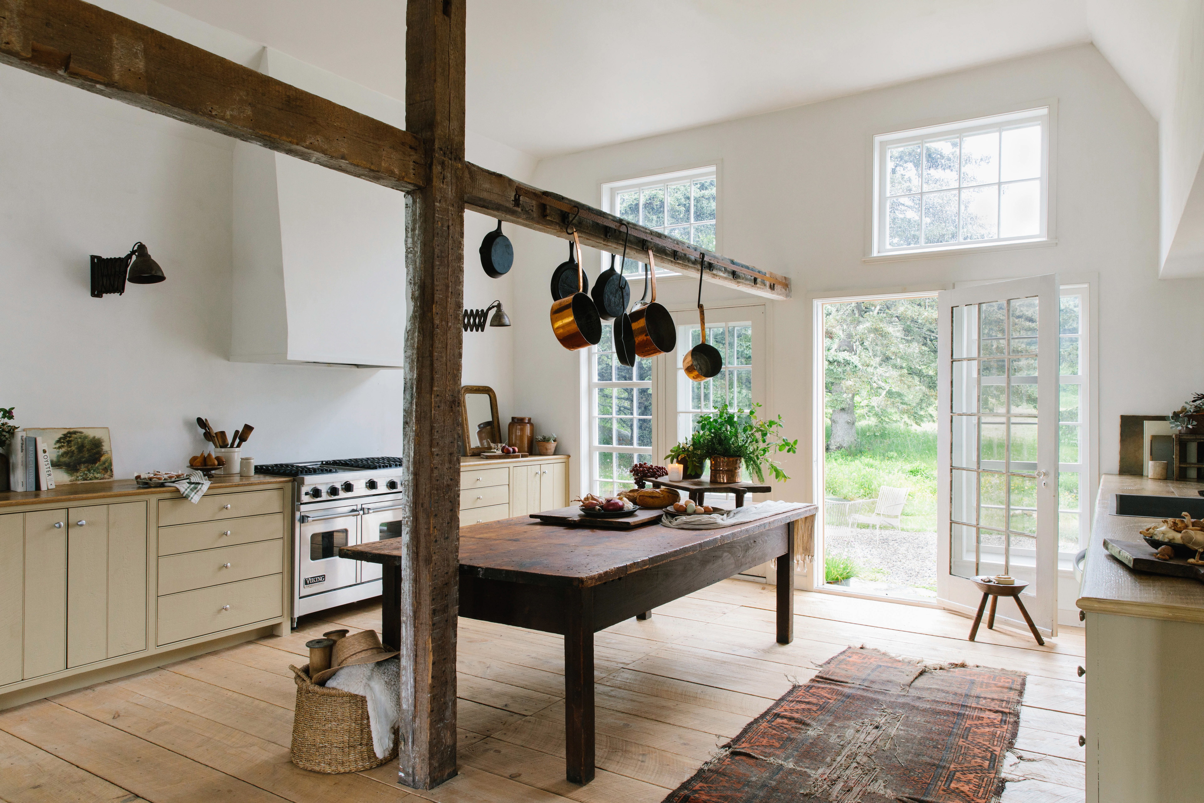 a kitchen with a table, stove, oven, cabinets and windows