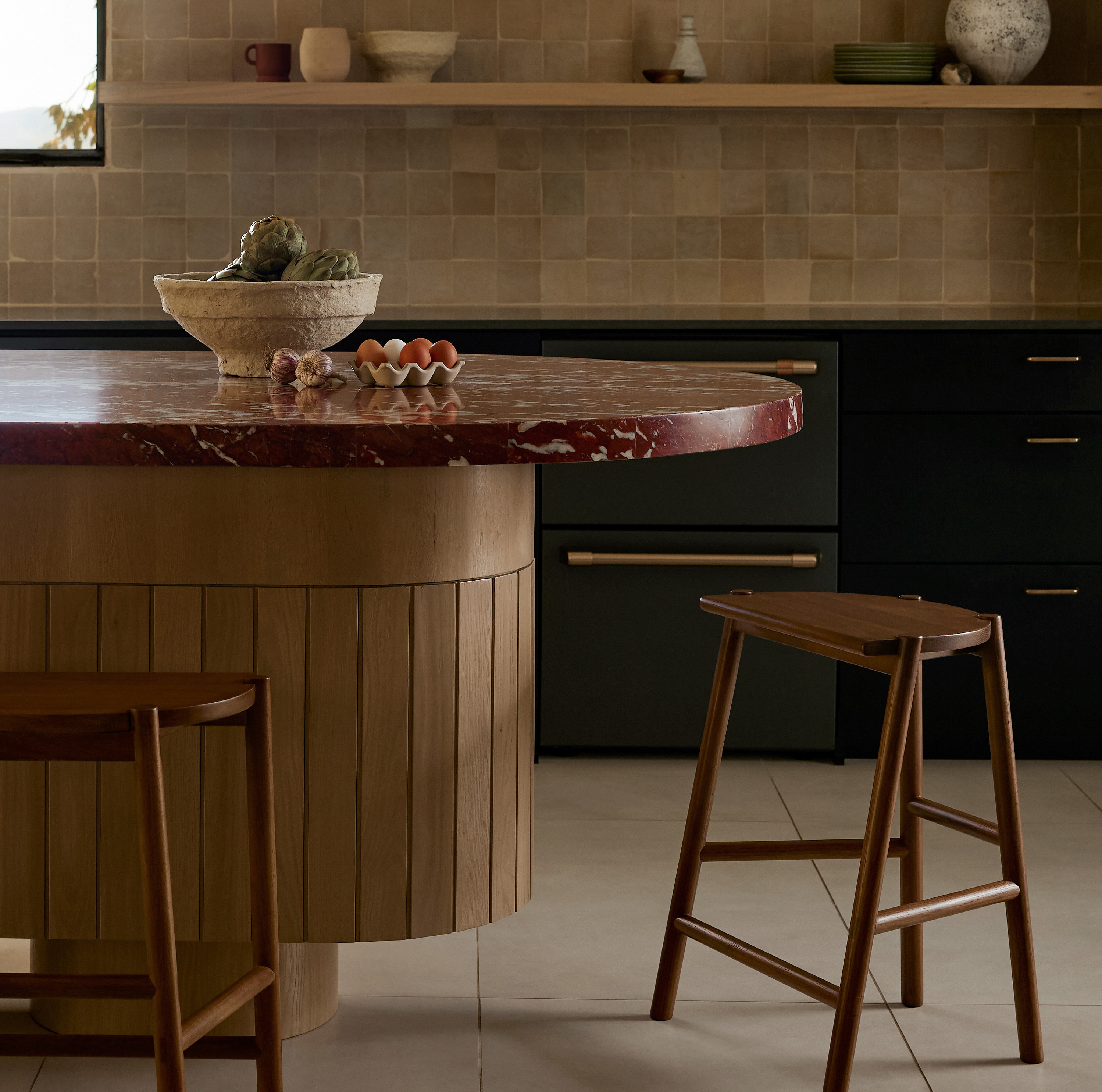 a kitchen with a counter, stools and shelves