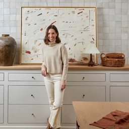 a woman standing in front of a painting in a kitchen