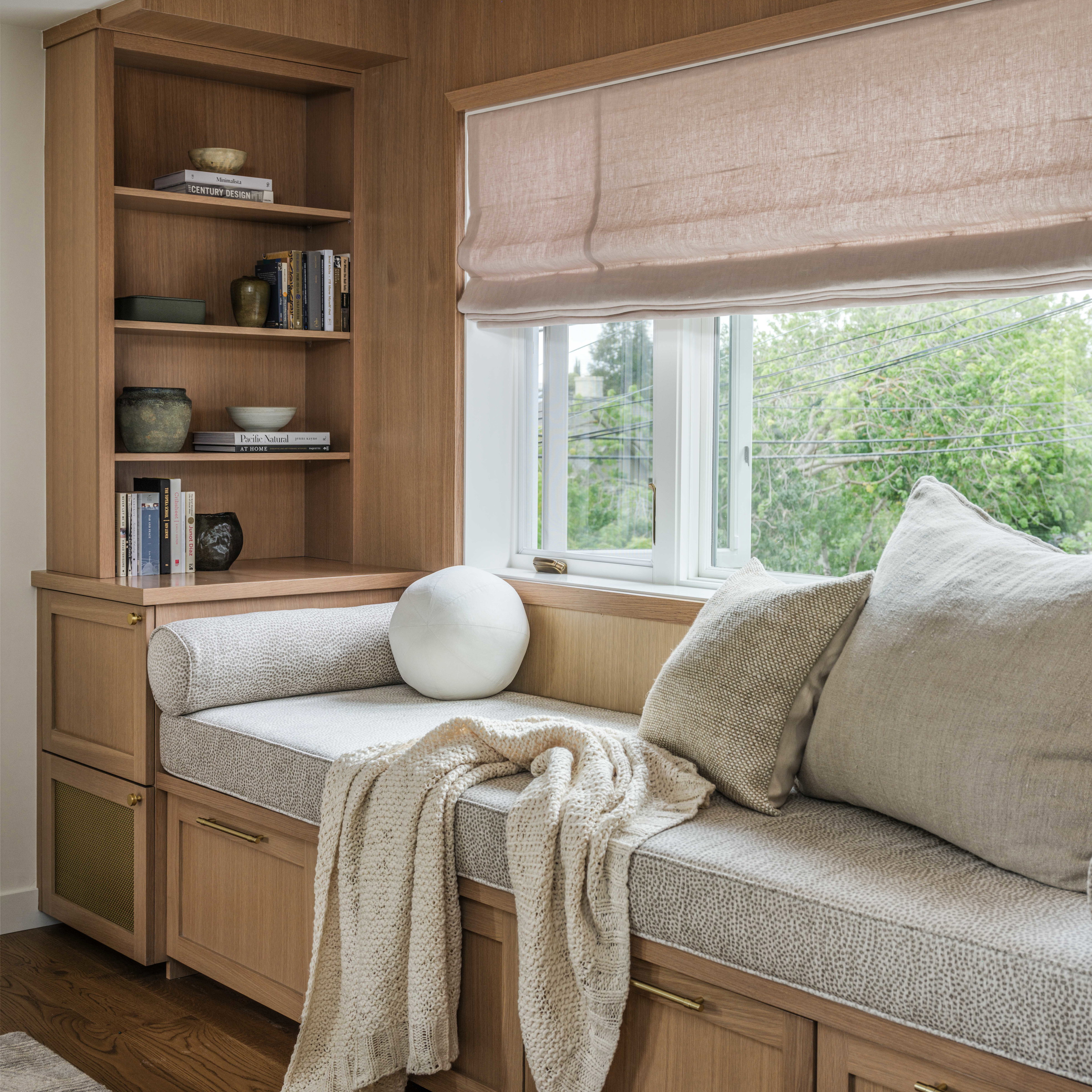 a window seat with pillows and a blanket on it