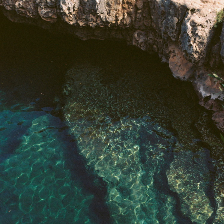 a body of water surrounded by a rocky cliff