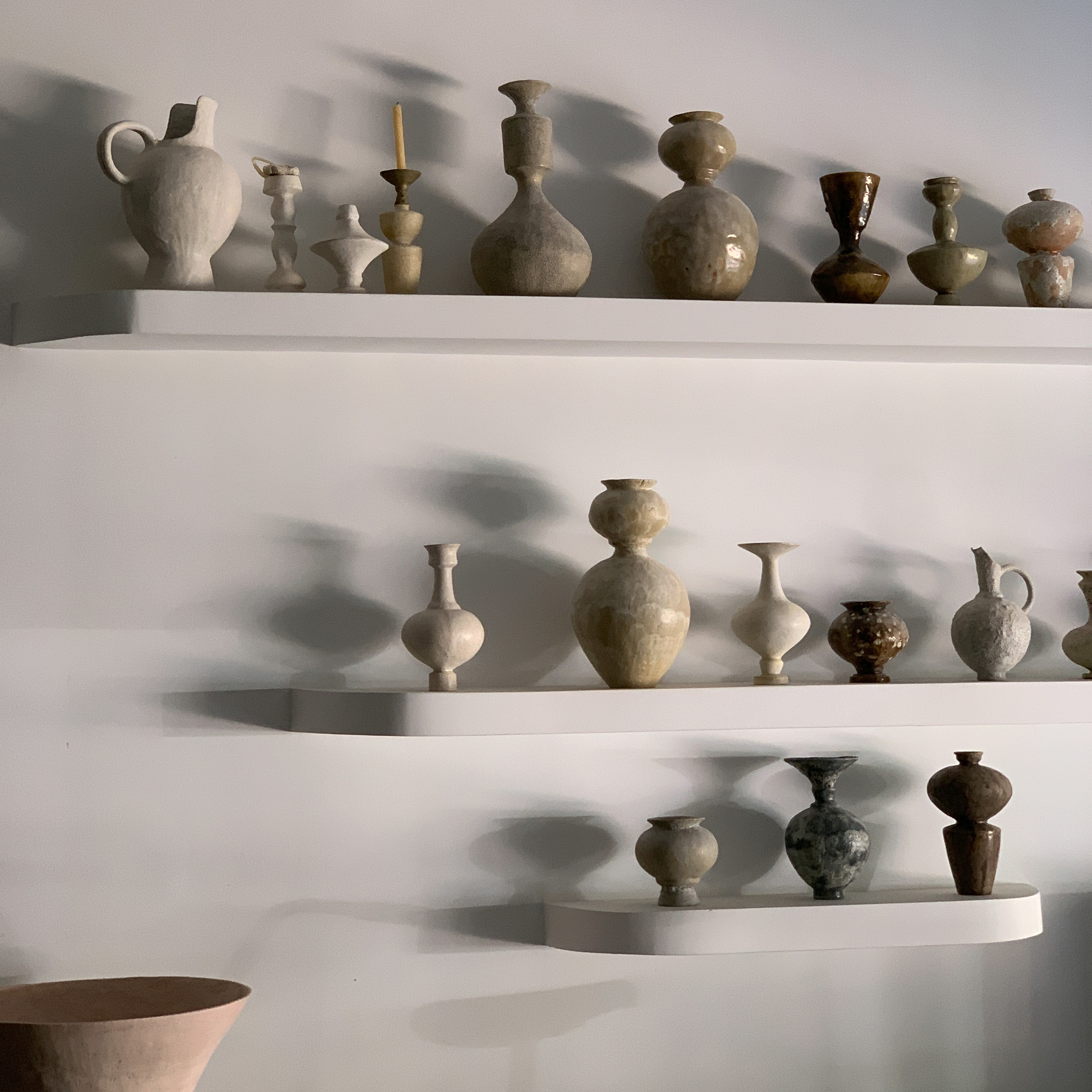 a shelf filled with lots of vases on top of white shelves