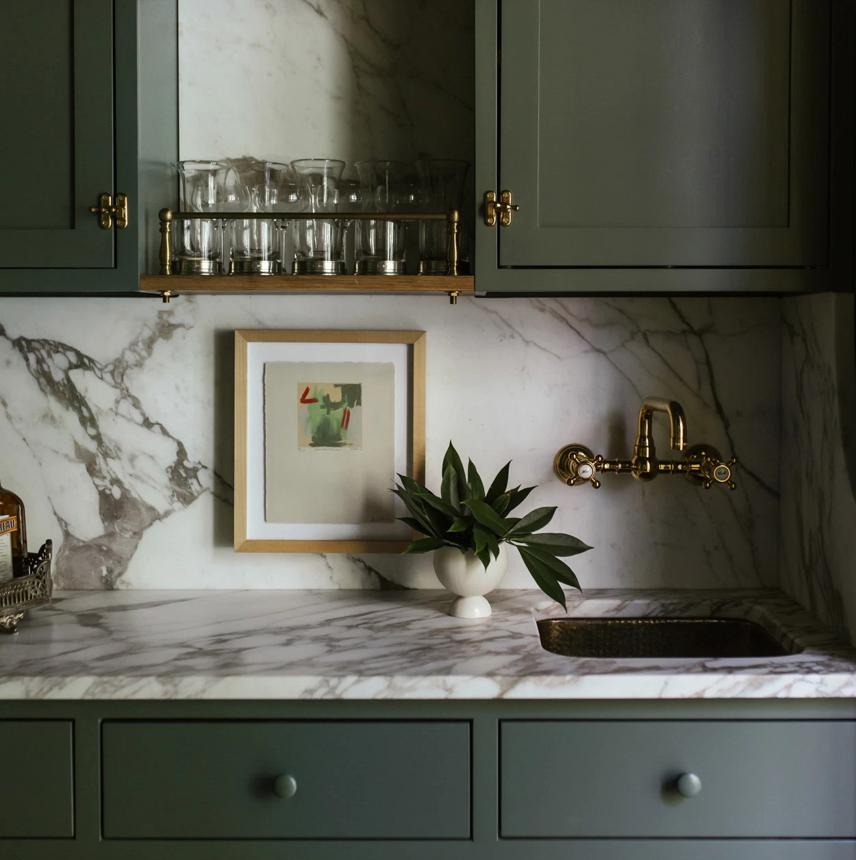 a kitchen with green cabinets and marble counter tops