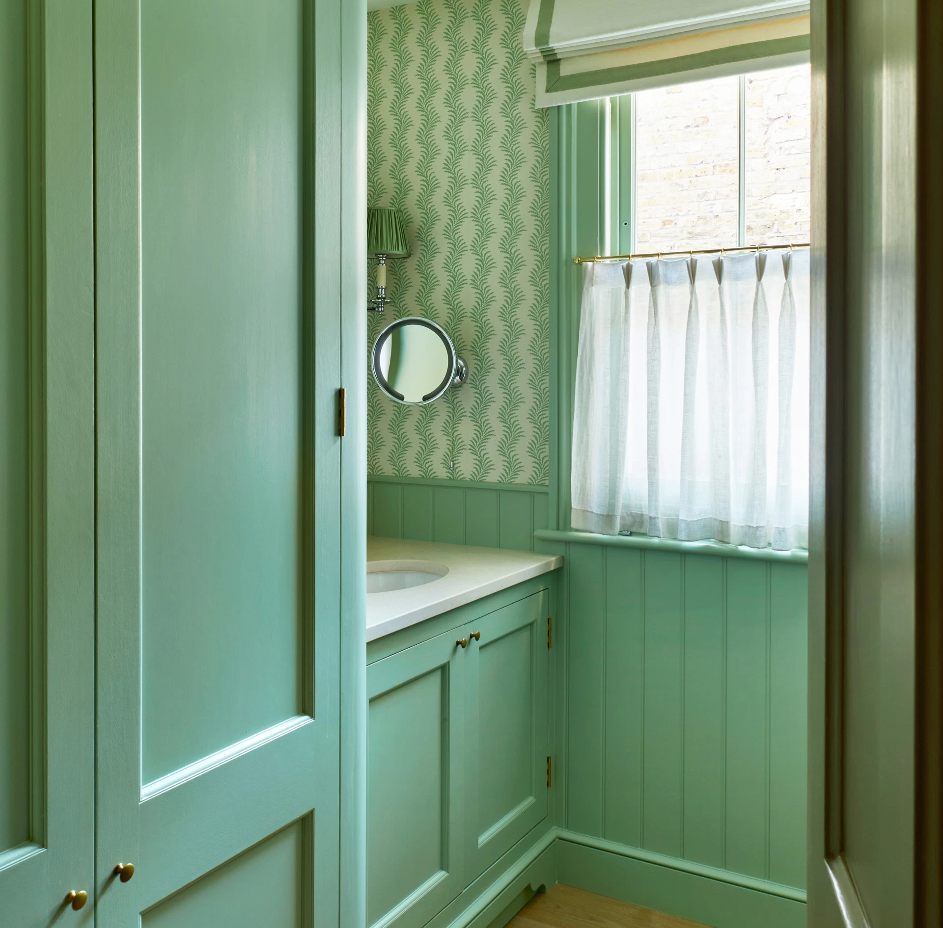 a green bathroom with a window and a rug