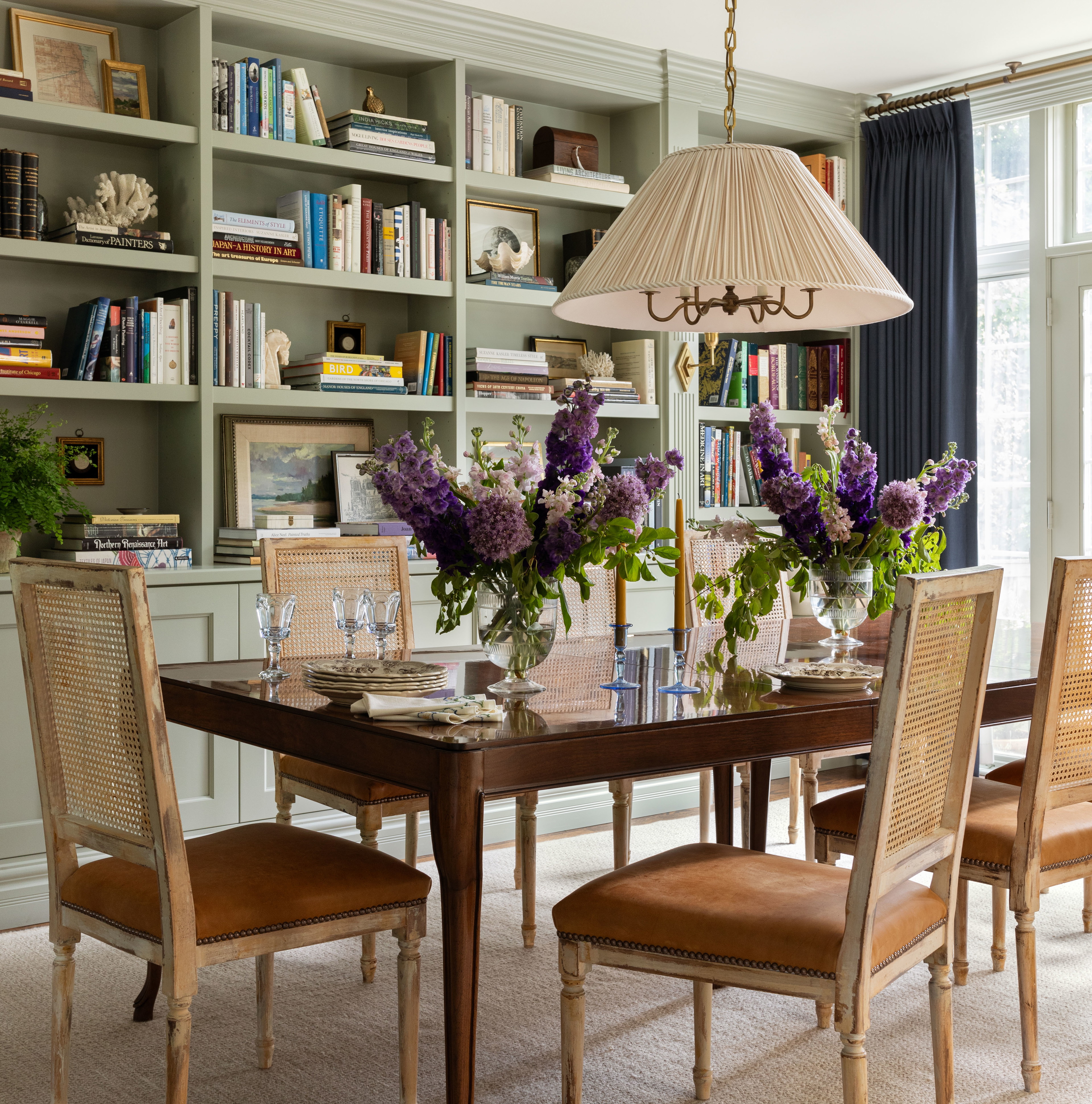 a dining room table with chairs and a vase of flowers