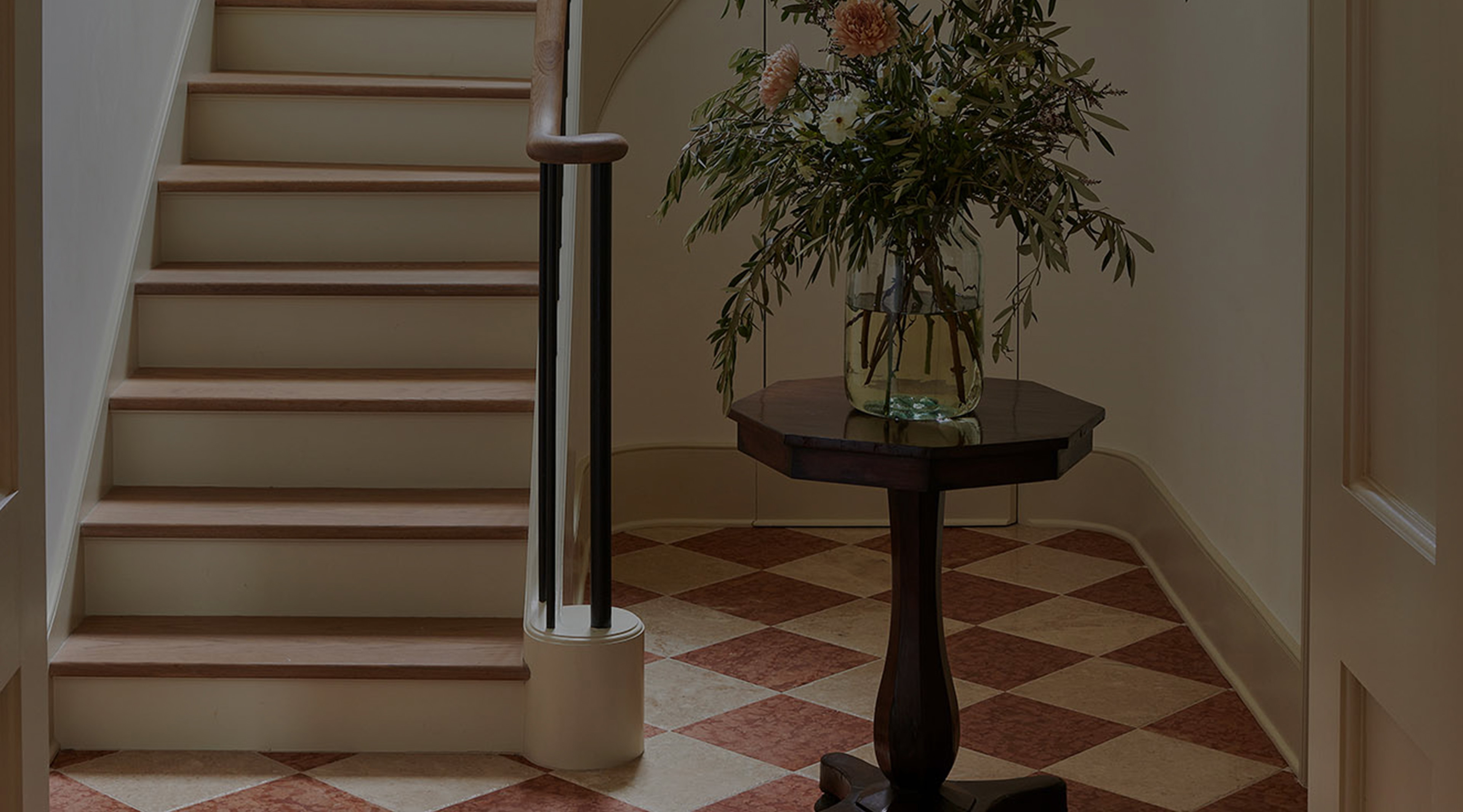 a vase of flowers sitting on a table next to a stair case