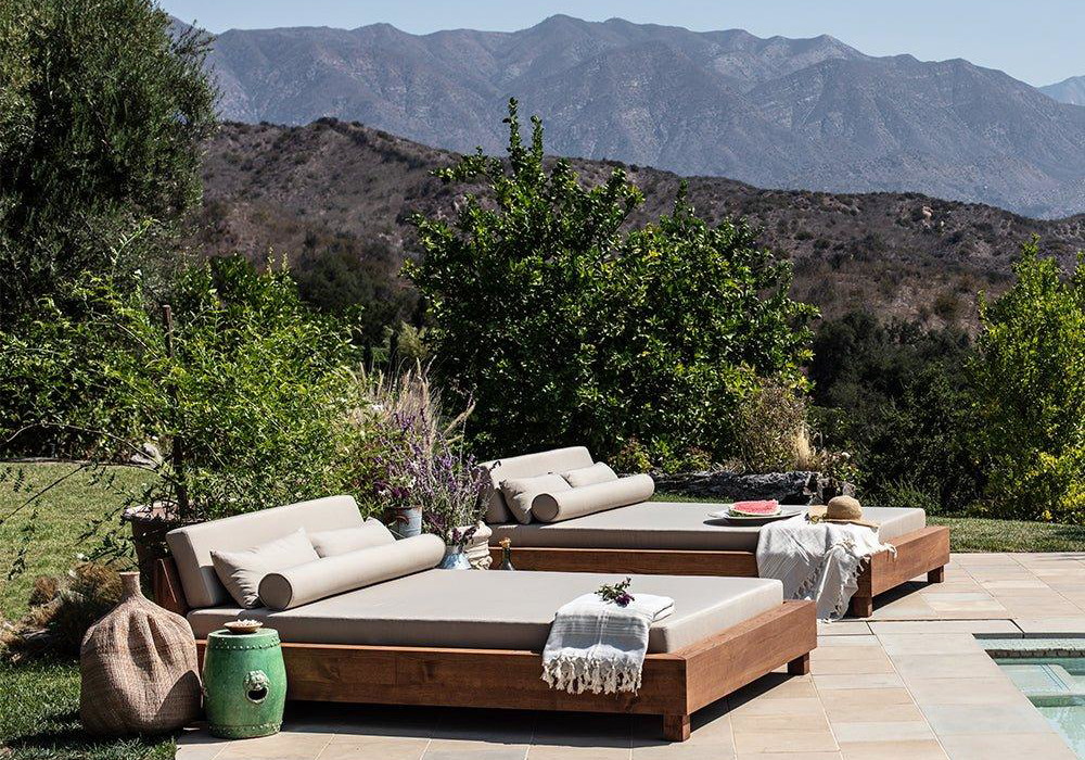 a couch sitting on top of a stone patio next to a swimming pool