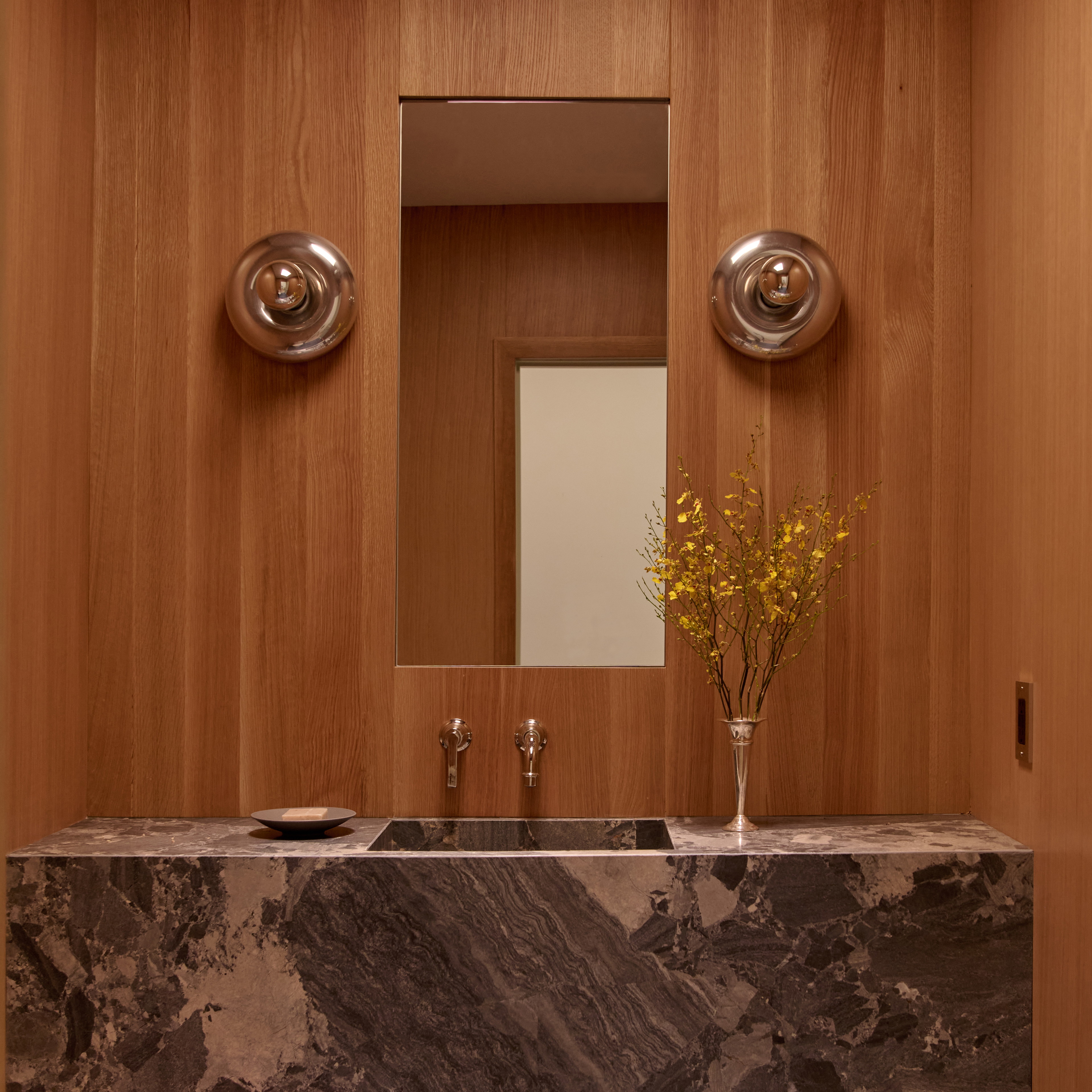 a bathroom with a marble sink and wooden walls