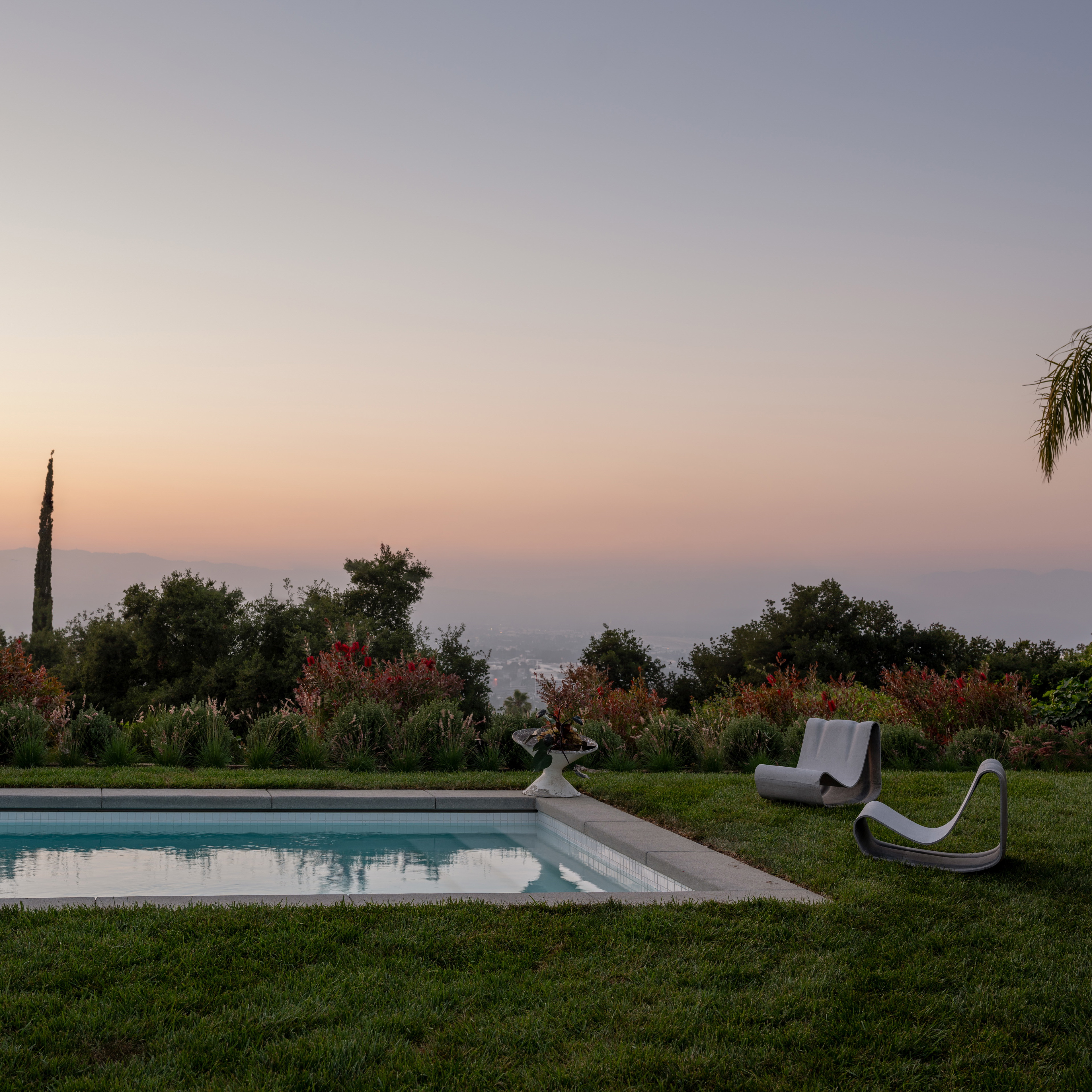 a pool in the middle of a lush green field