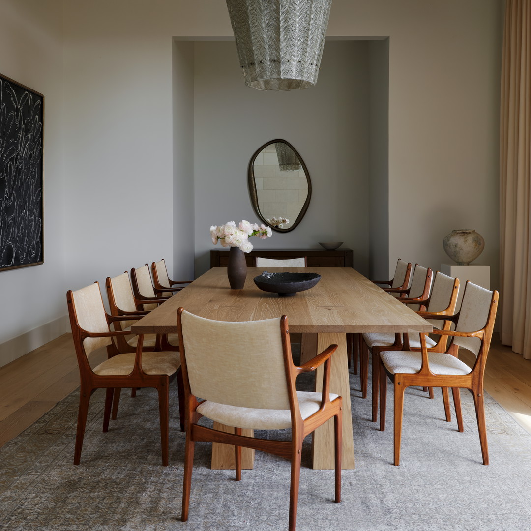 a dining room table with chairs and a vase of flowers