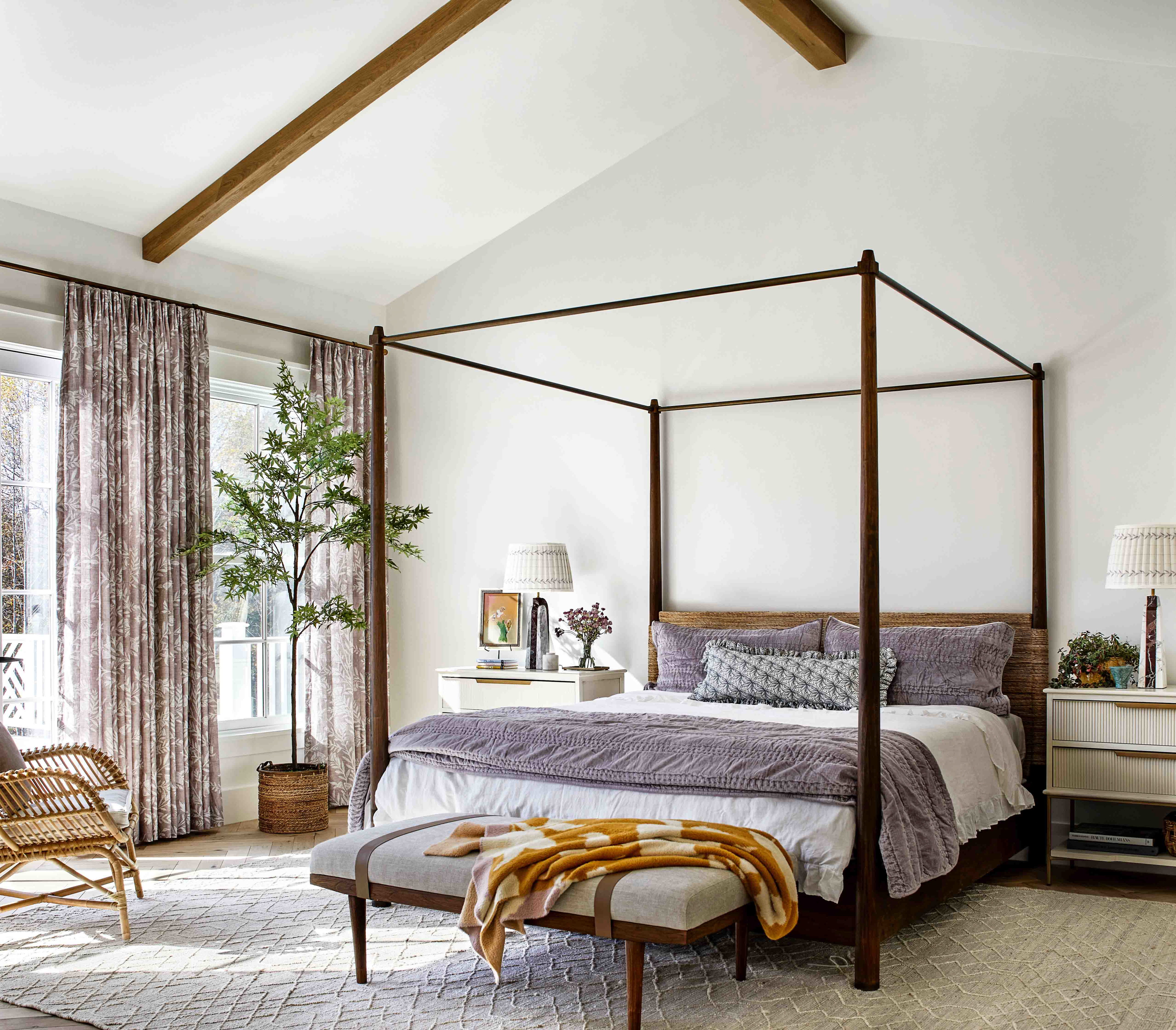 a bedroom with a canopy bed and a wicker chair