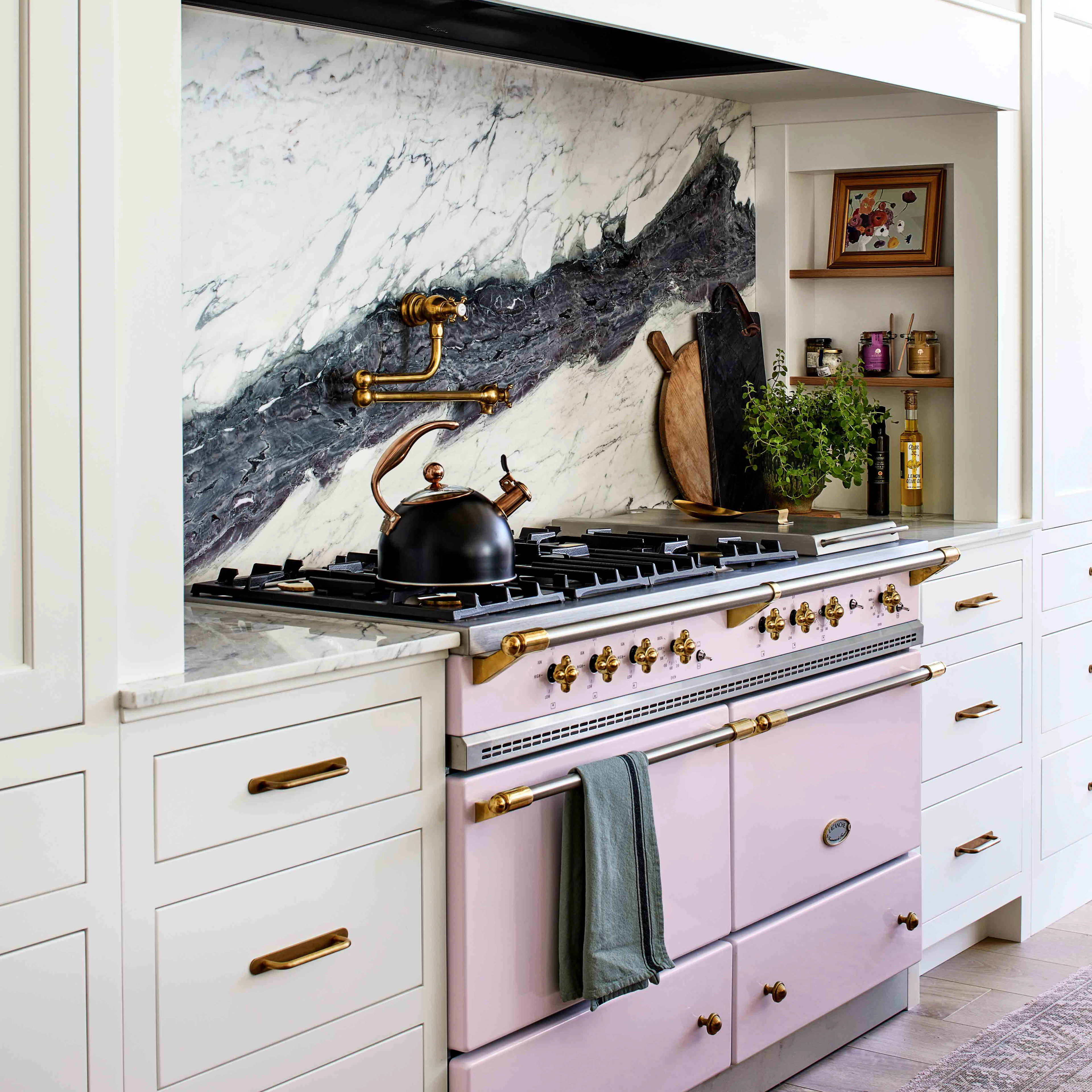 a kitchen with a pink stove and white cabinets