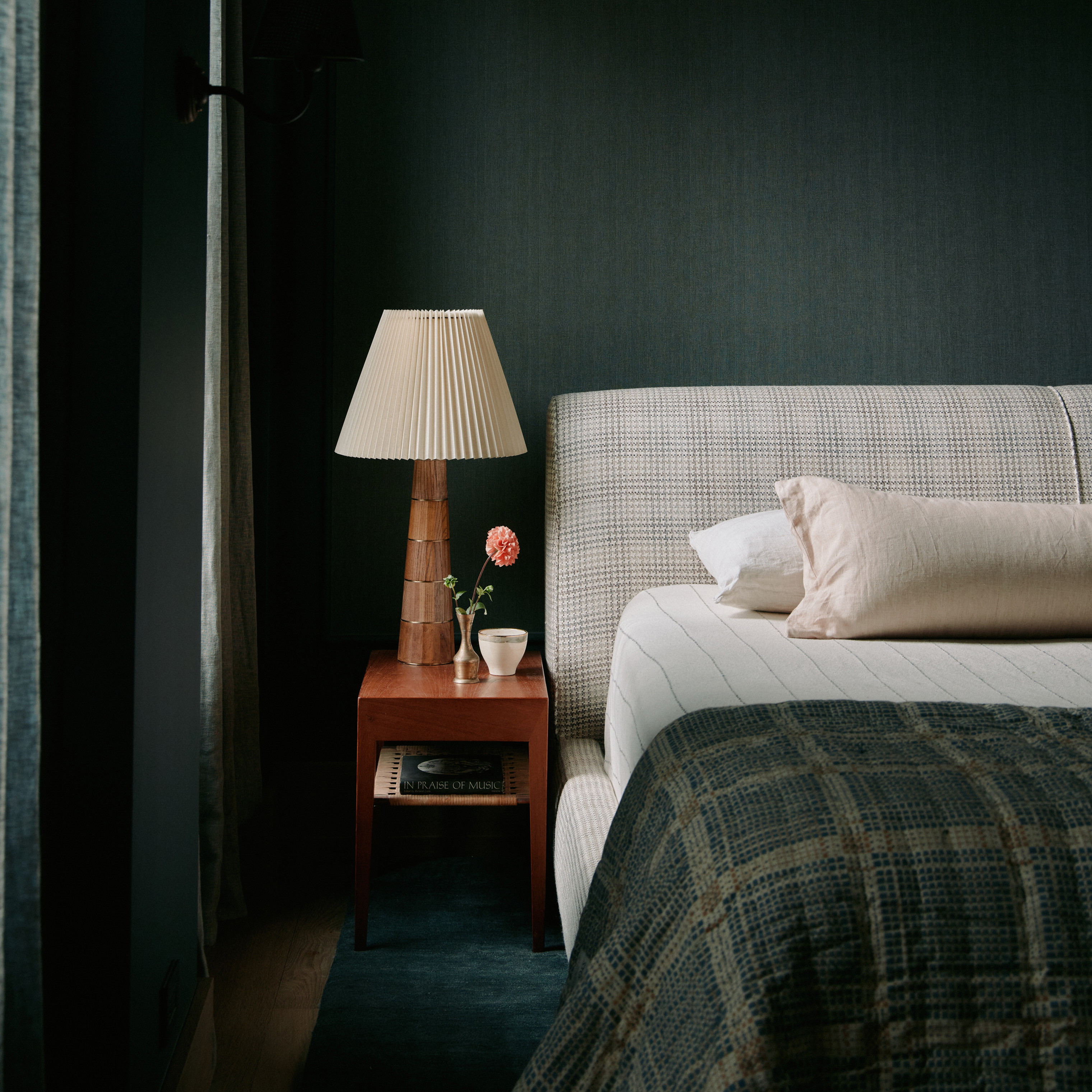 a bed sitting next to a night stand with a lamp on top of it