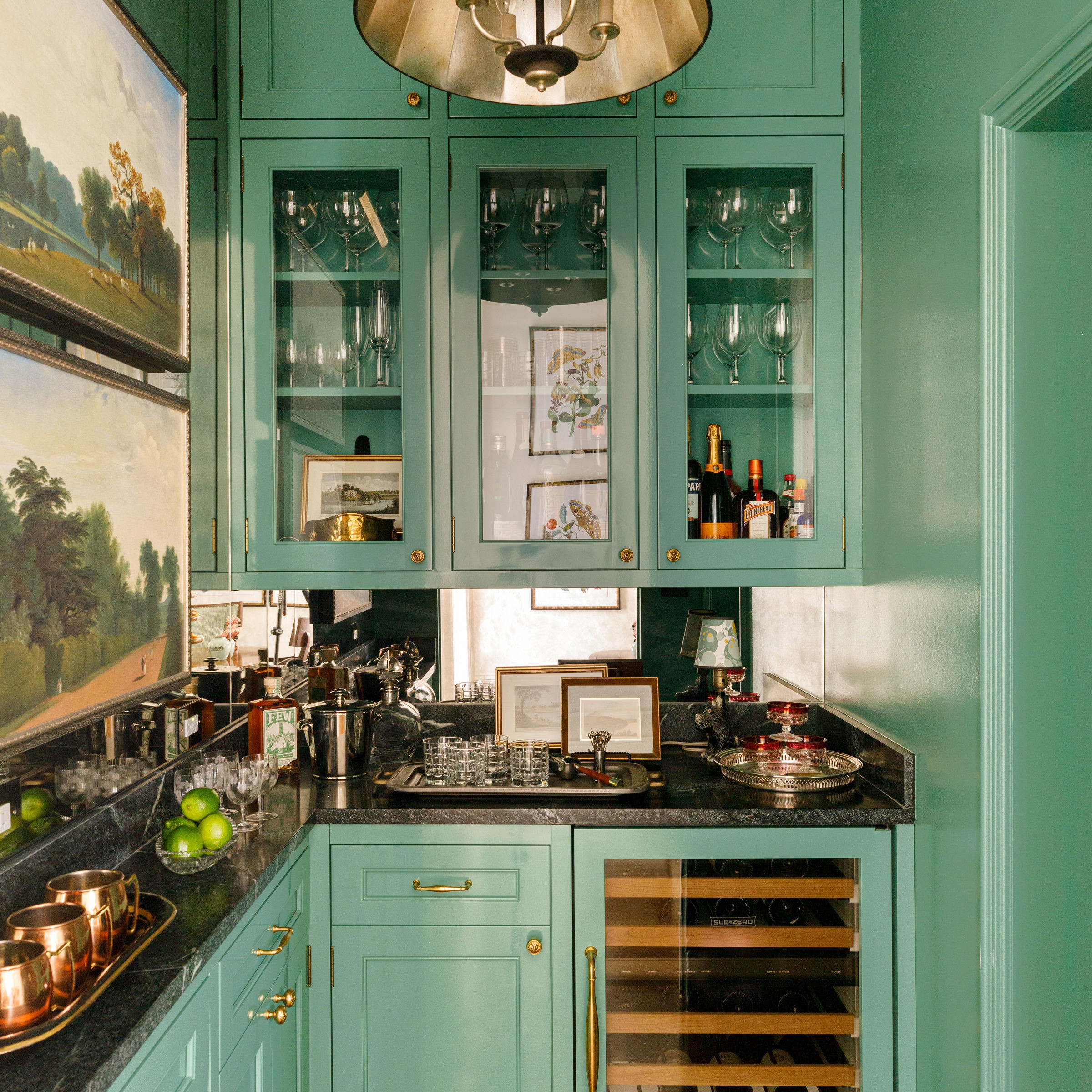 a kitchen with green cabinets and a painting on the wall