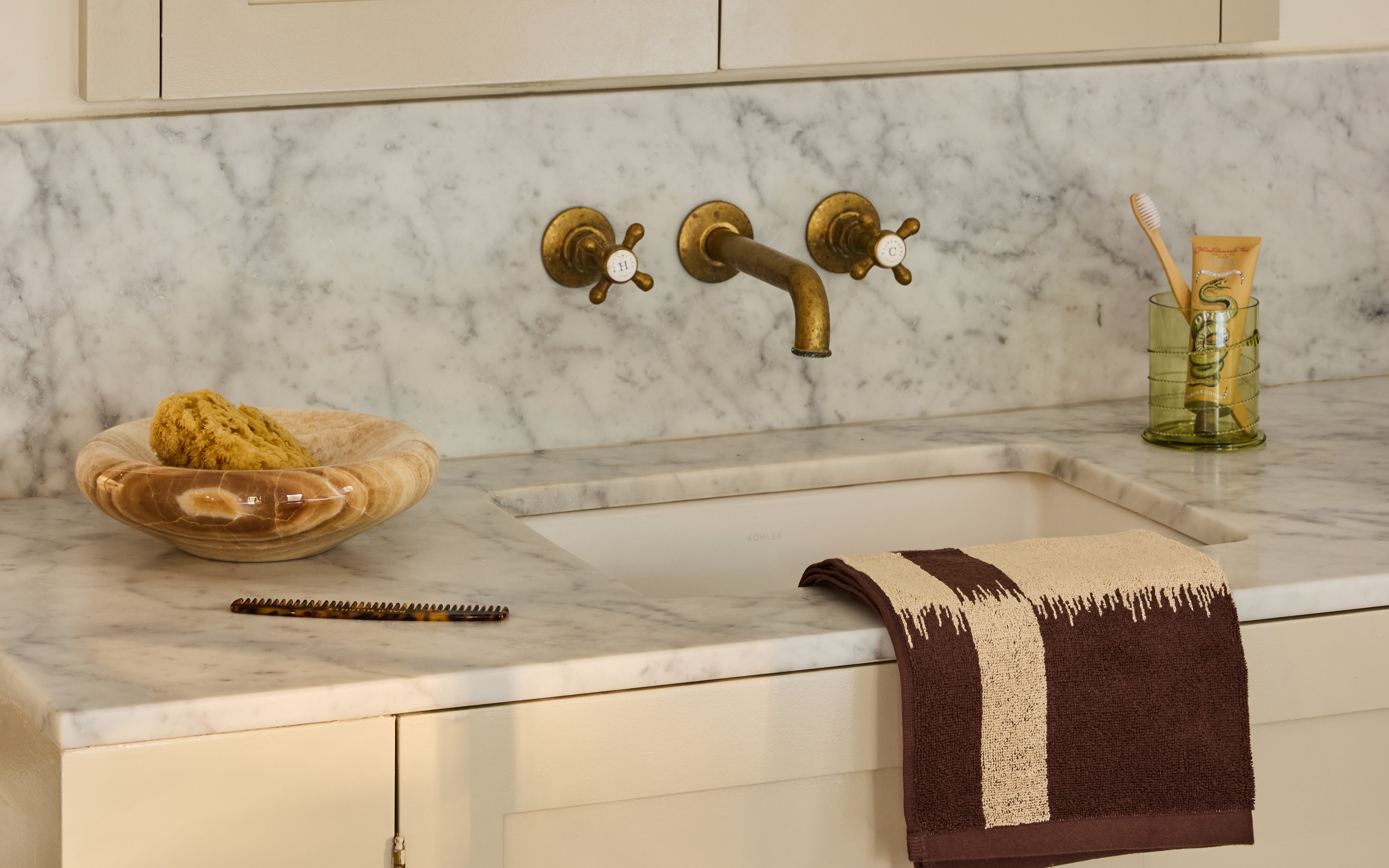 a white kitchen with marble counter tops and gold faucets