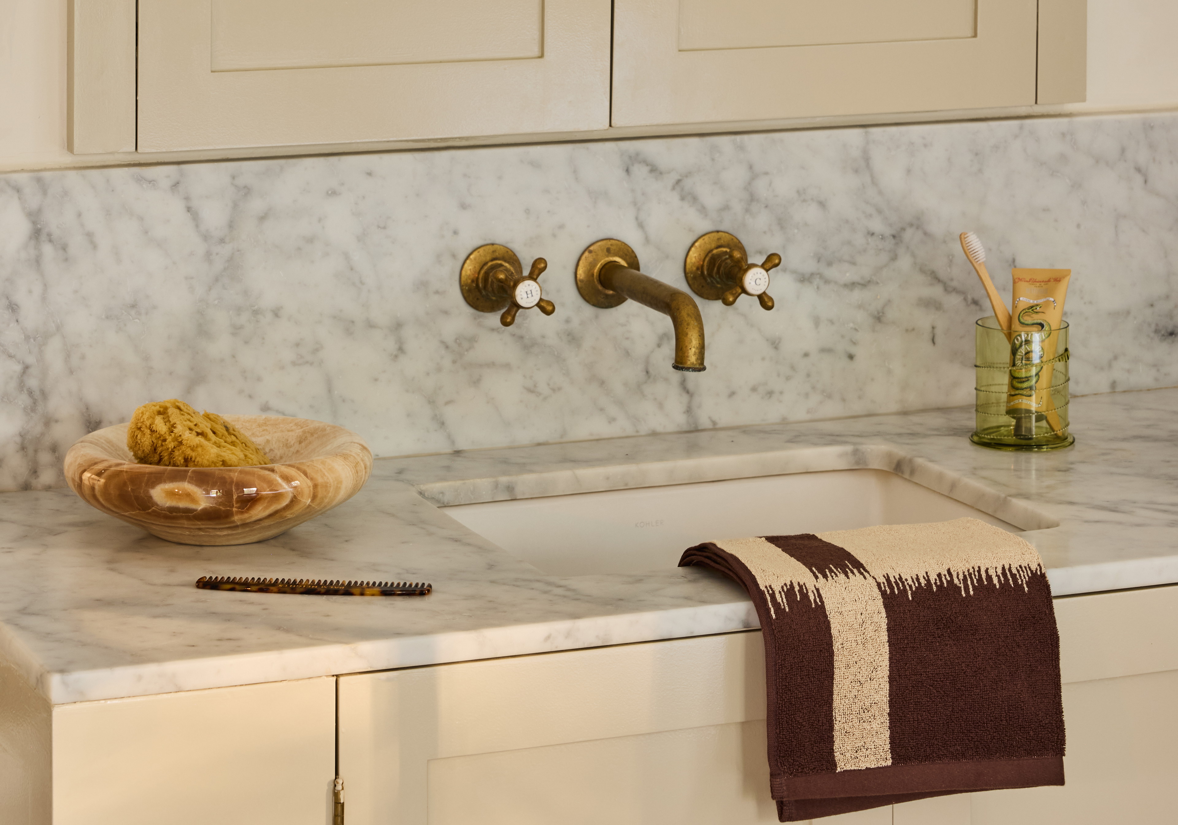 a white kitchen with marble counter tops and gold faucets